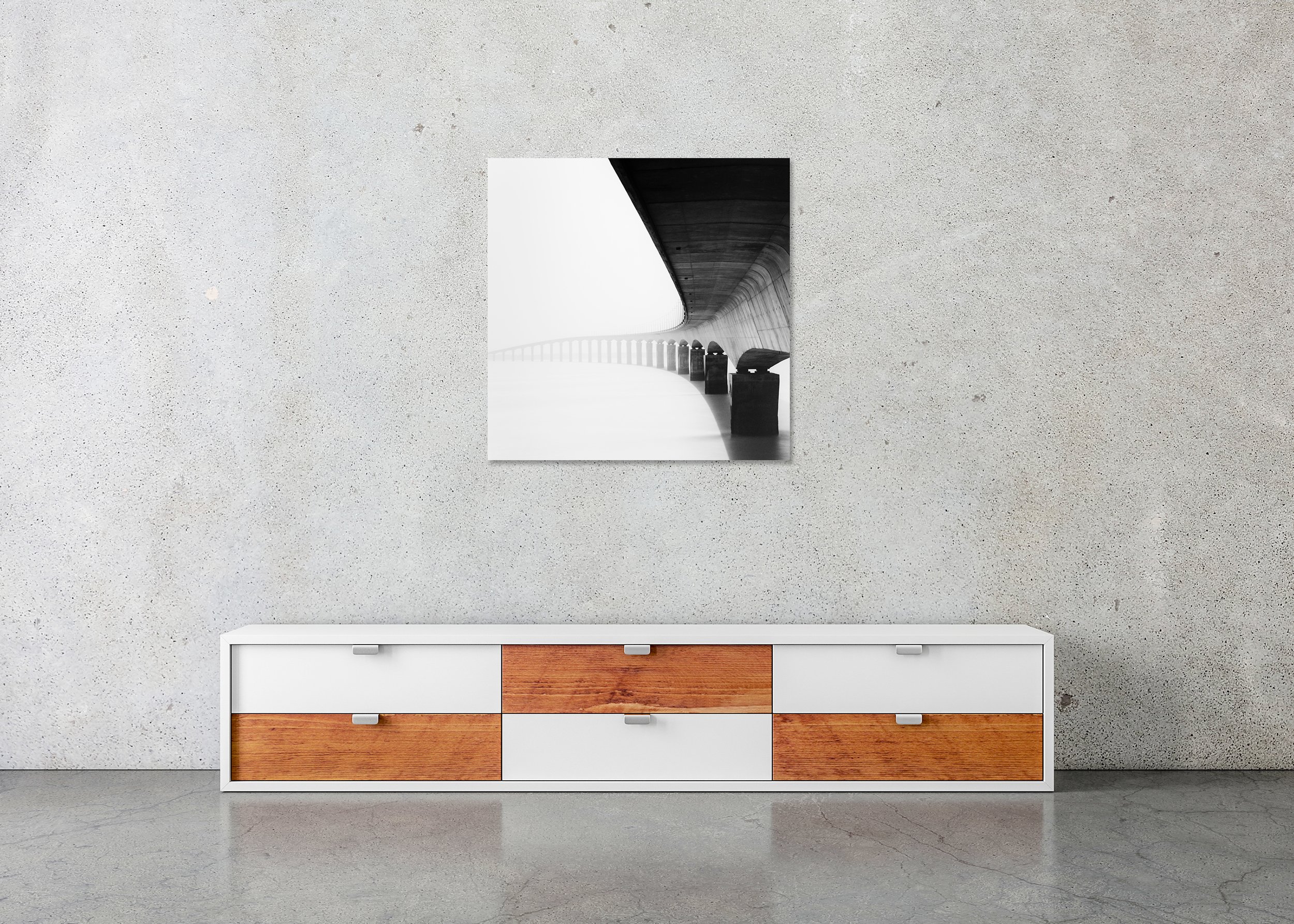 Île de Ré Bridge Study 1 displayed above a low cabinet as a frameless black-and-white aluminium Dibond print by Gerald Berghammer.
