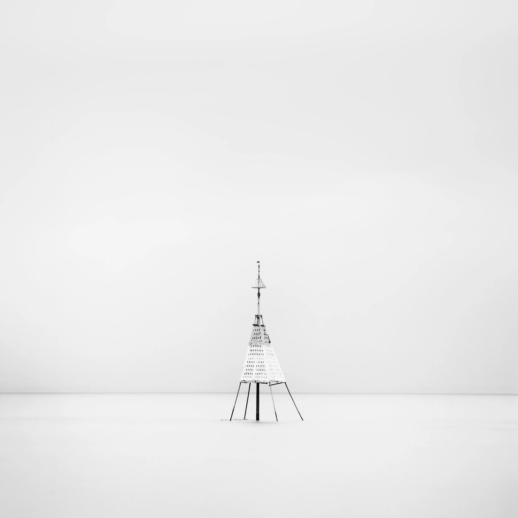 Gerald Berghammer - Black and white long exposure seascape photography. Solitary metal structure lighthouse with a conical top, standing in the Ocean.