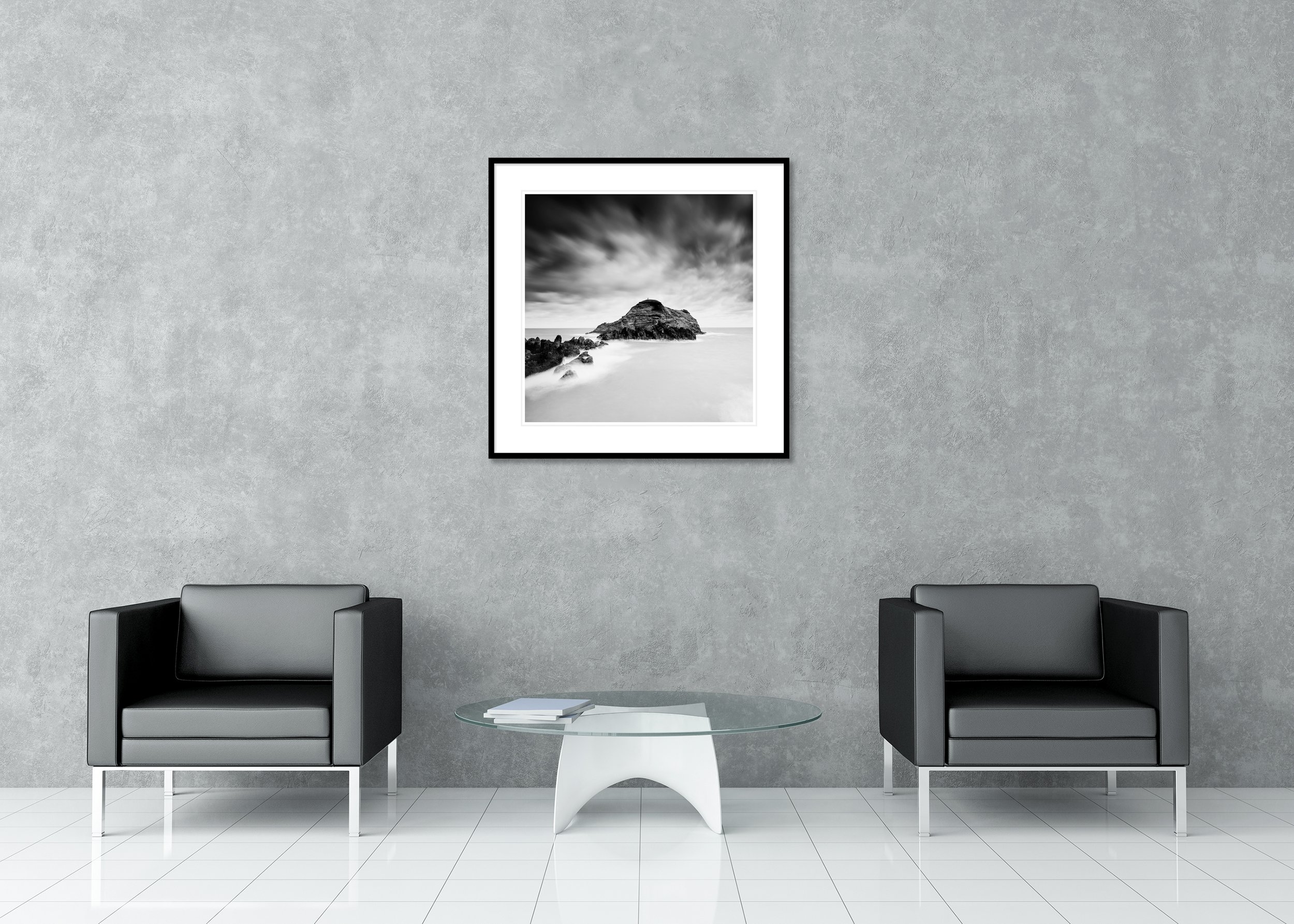 Black-and-white long-exposure seascape of a rocky island beneath dramatic clouds, archival pigment print in a classic frame with passe-partout.