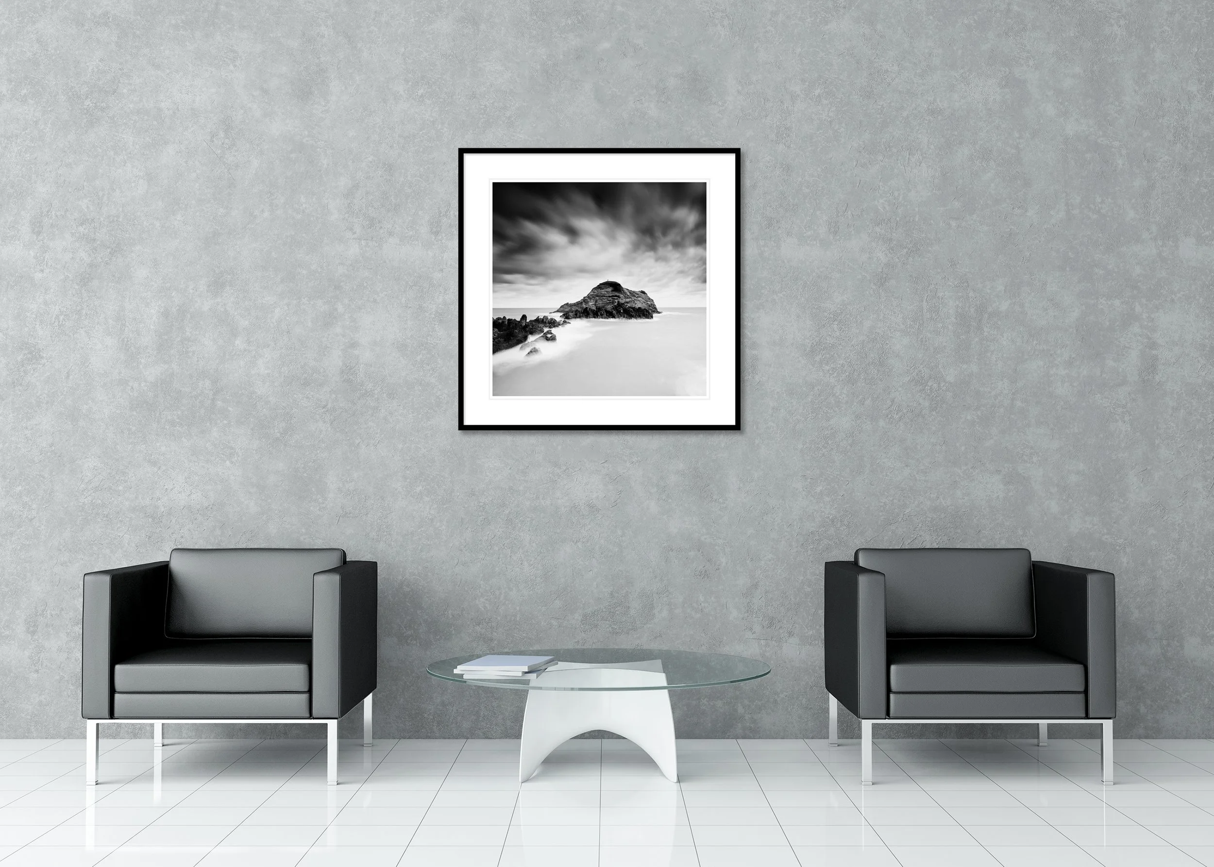 Black-and-white long-exposure seascape of a rocky island beneath dramatic clouds, archival pigment print in a classic frame with a mount.
