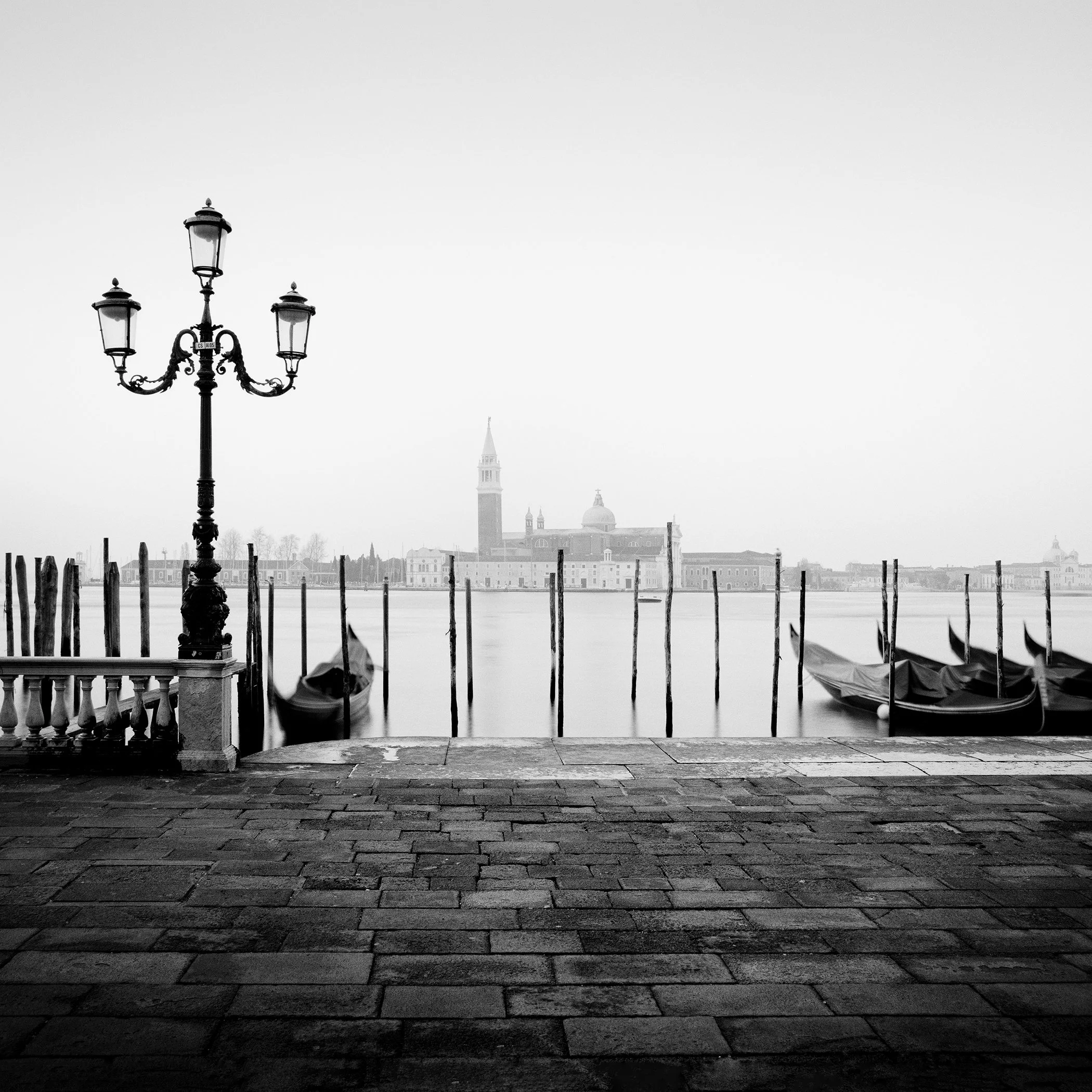 Minimal black-and-white Venice scene with street lamp, gondolas and San Giorgio Maggiore by Gerald Berghammer