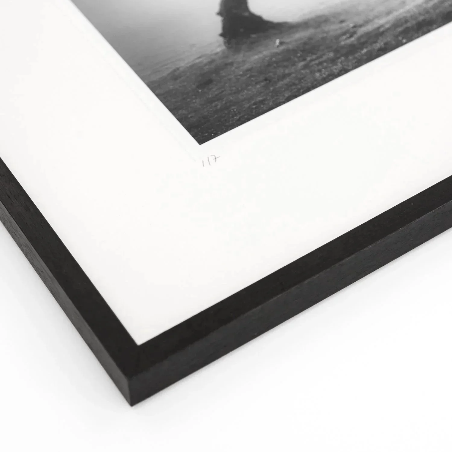 Close-up of the handwritten edition number 1/7 and black wooden frame of Gerald Berghammer's photograph.