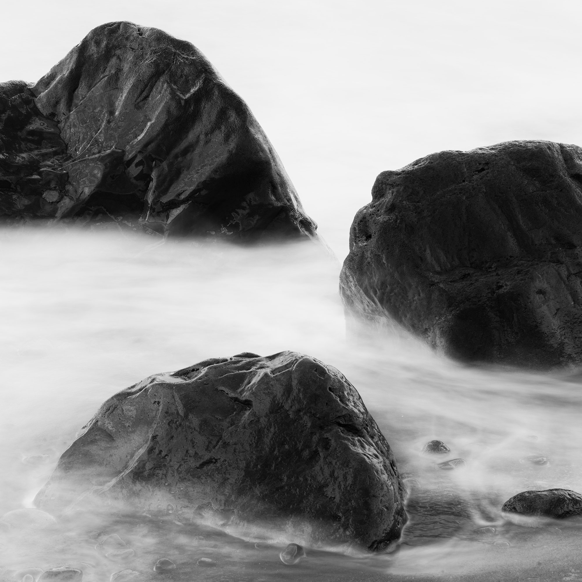 Detail view of Black Rocks and a Few Stones showing beach stones, surf and monochrome texture.