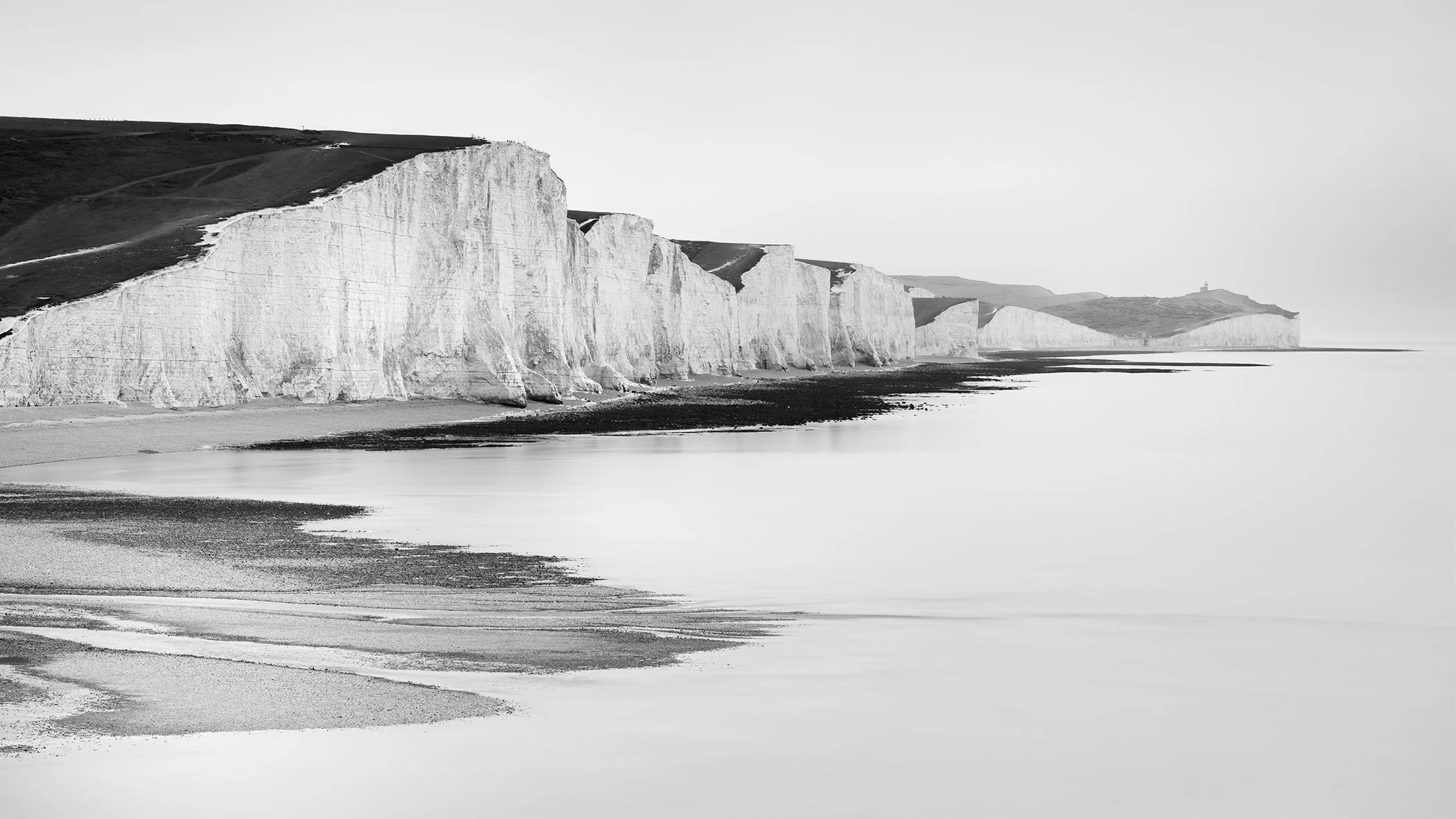 Seven Sisters chalk cliffs in East Sussex, UK, reflected in calm sea water, black and white landscape