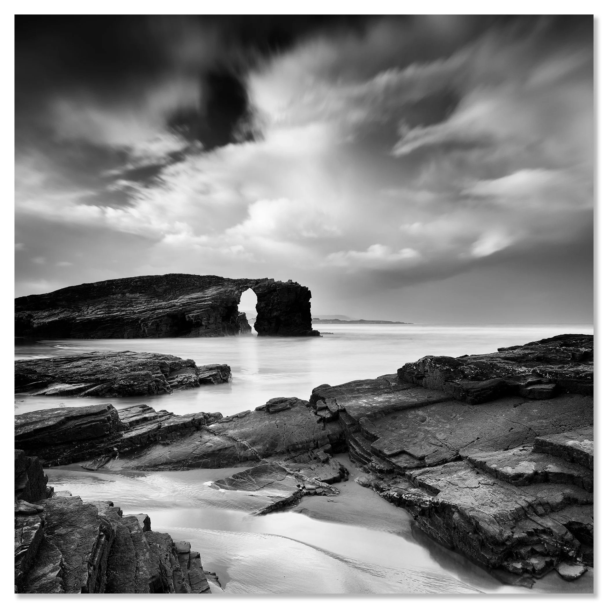 Monochrome seascape featuring layered rocks, a natural sea arch and stormy skies – dibond frameless