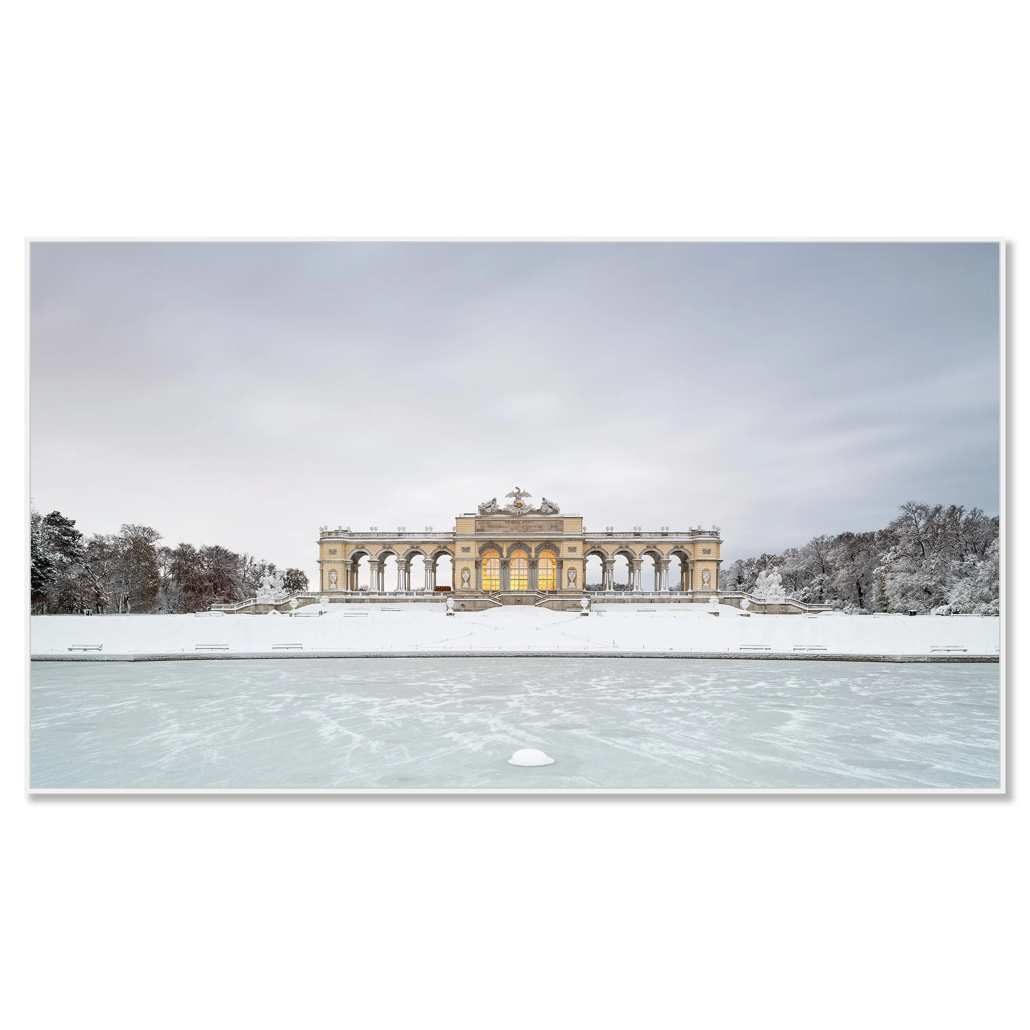 Gerald Berghammer - Color Photography. A historic building on a snow-covered landscape, surrounded by leafless trees, with a frozen body of water. Chromaluxe framed white