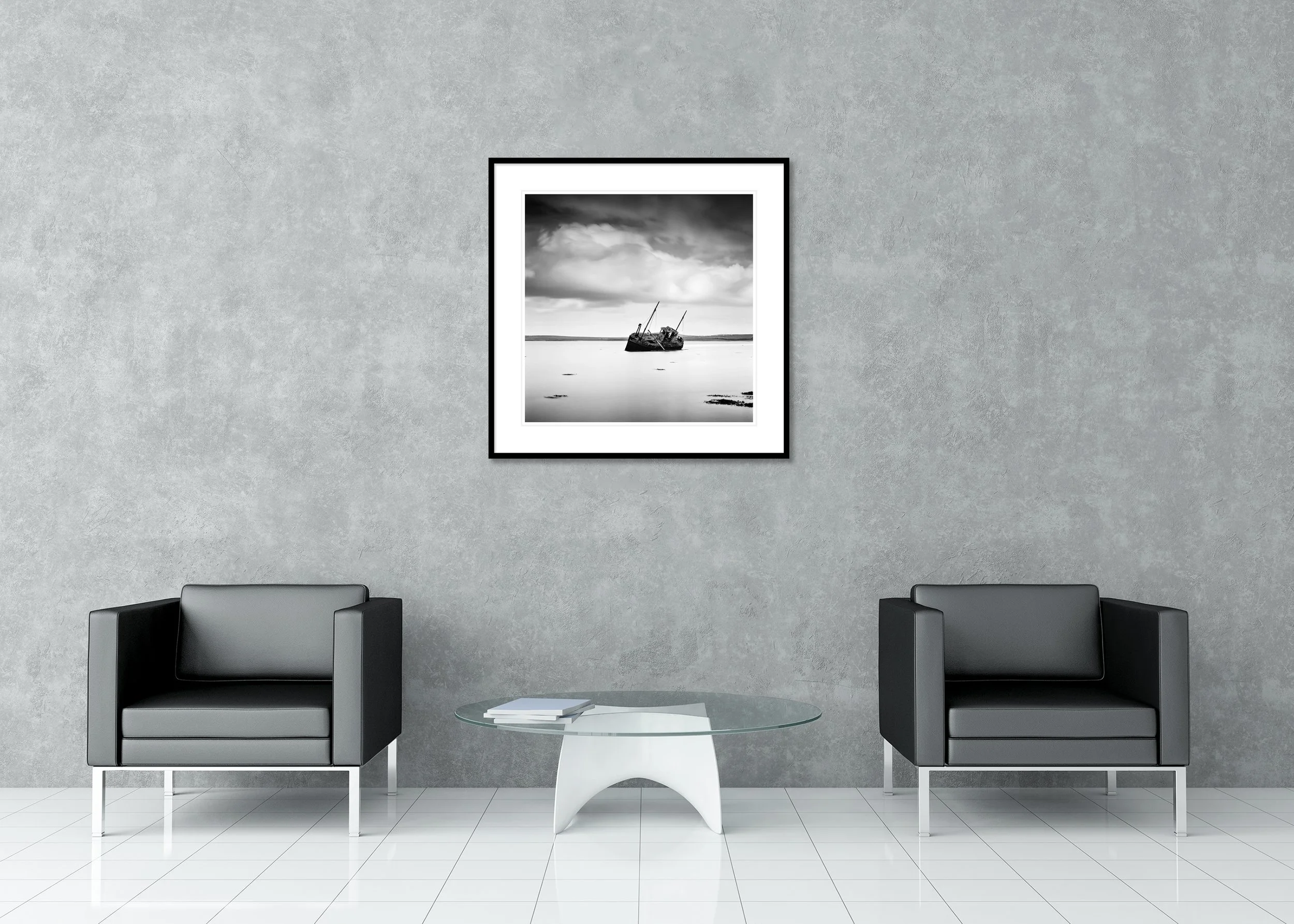 Black-and-white archival pigment print of an abandoned boat on calm water in Ireland beneath dramatic clouds, classic frame with mount