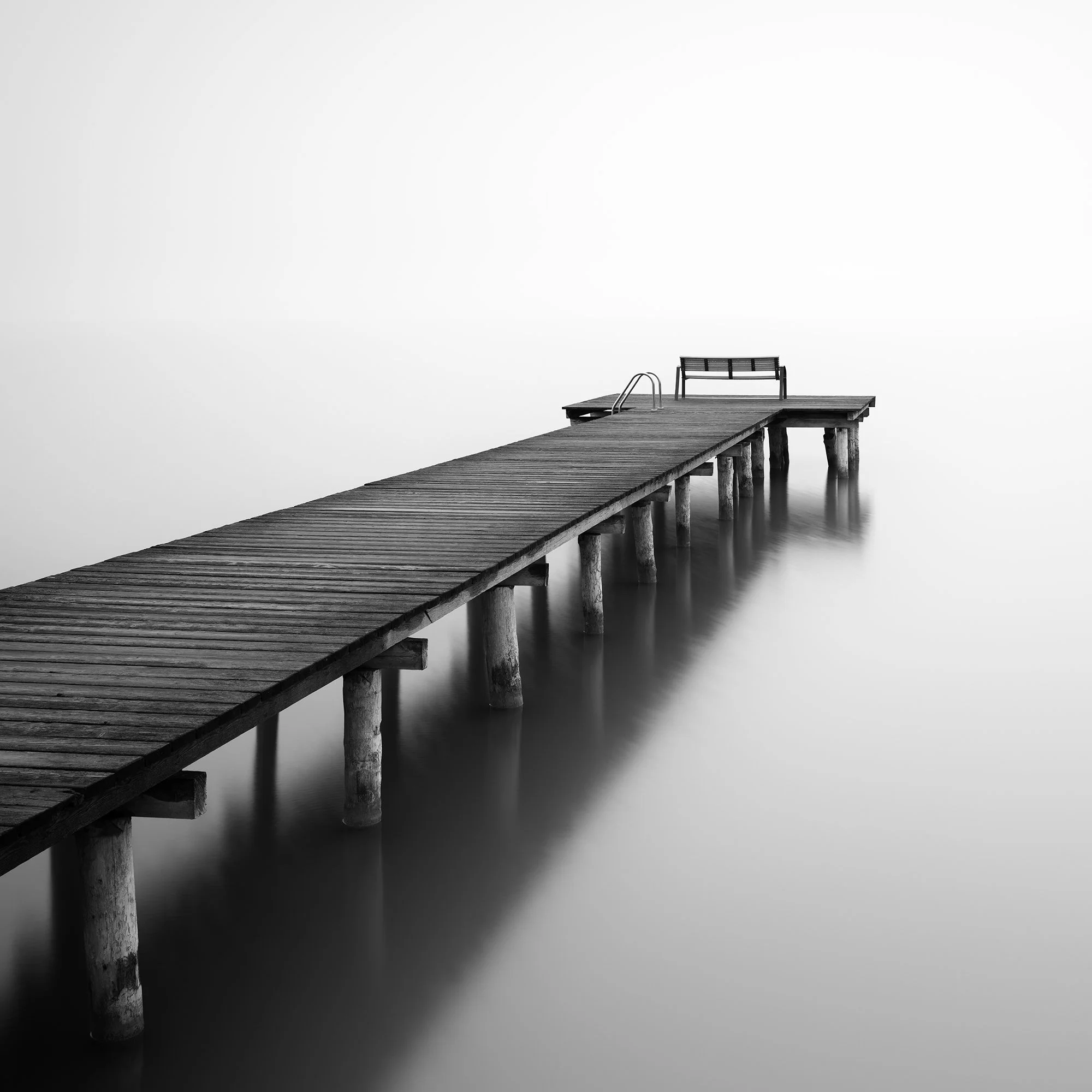Into the Nothing Study 1 by Gerald Berghammer, minimalist black-and-white long-exposure photograph of a wooden jetty extending into calm water in Austria.