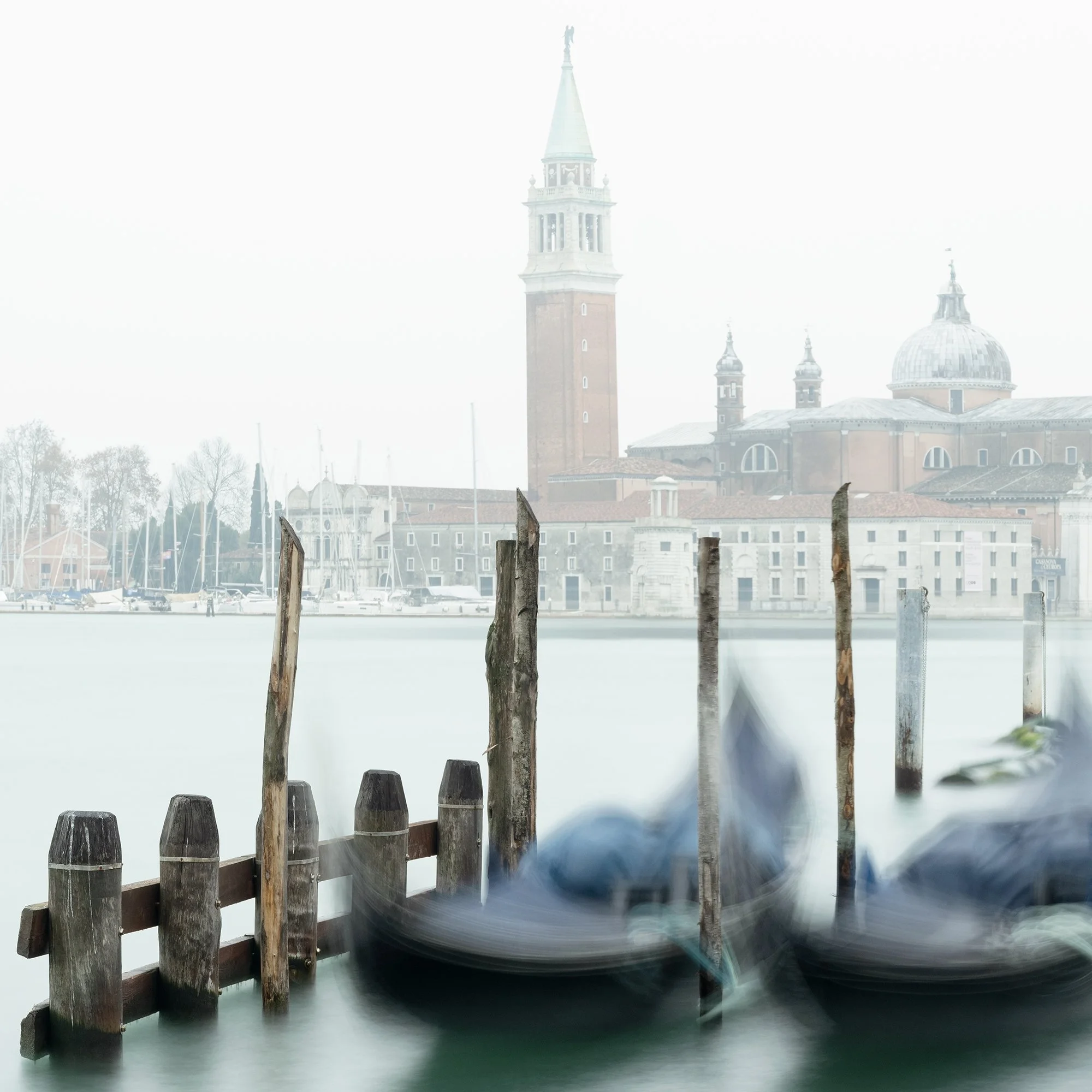 Gerald Berghammer - Color cityscape photography. Gondolas docked along wooden posts on a misty water canal and in back San Giorgio Maggiore Church. Print detail 3