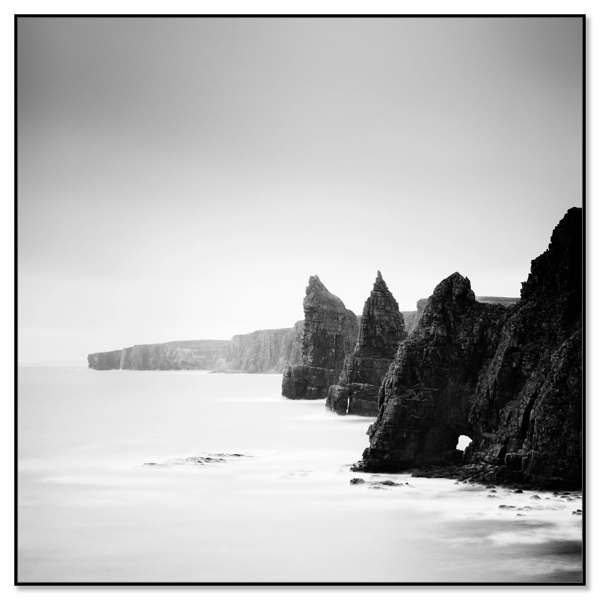 Black and white view of the Duncansby Stacks on the rocky coast of Scotland with calm sea – framed ArtBox black