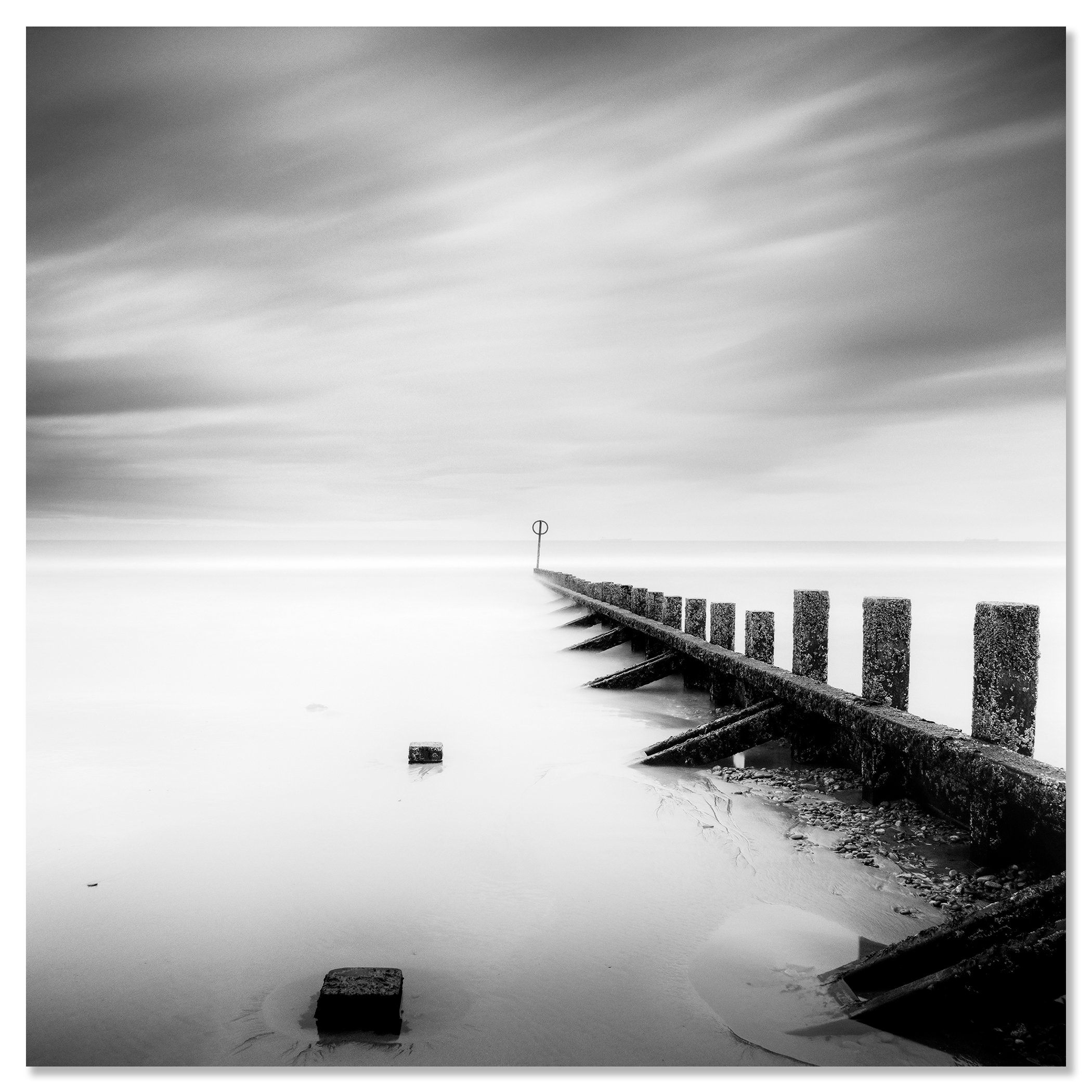 © 2012 Gerald Berghammer - Black and white landscape photography. A wooden wave breaker extending into a calm body of water, with a circular marker at the end. Chromaluxe frameless