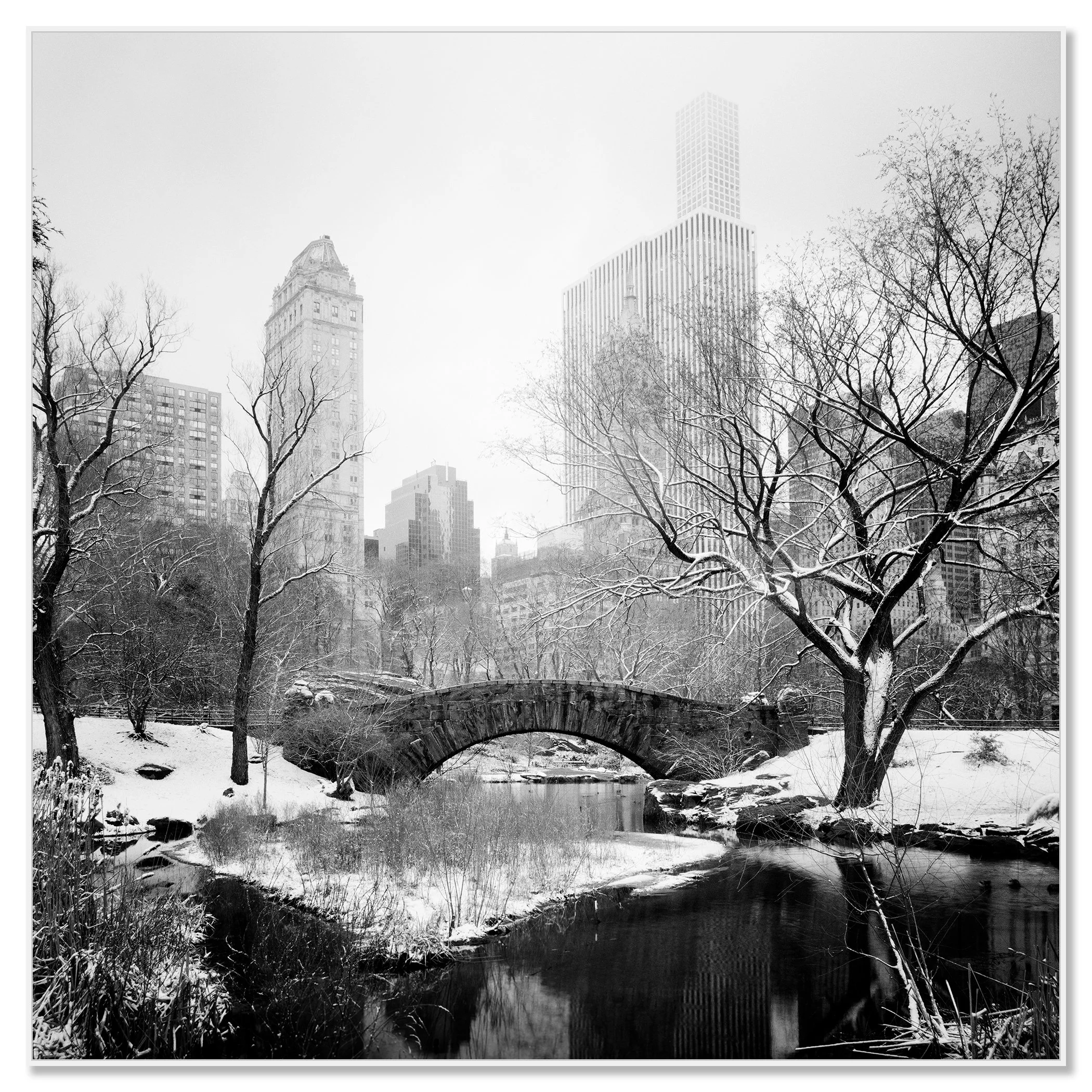 Central Park in winter with an old stone bridge, bare trees and tall buildings in New York City – framed ArtBox white