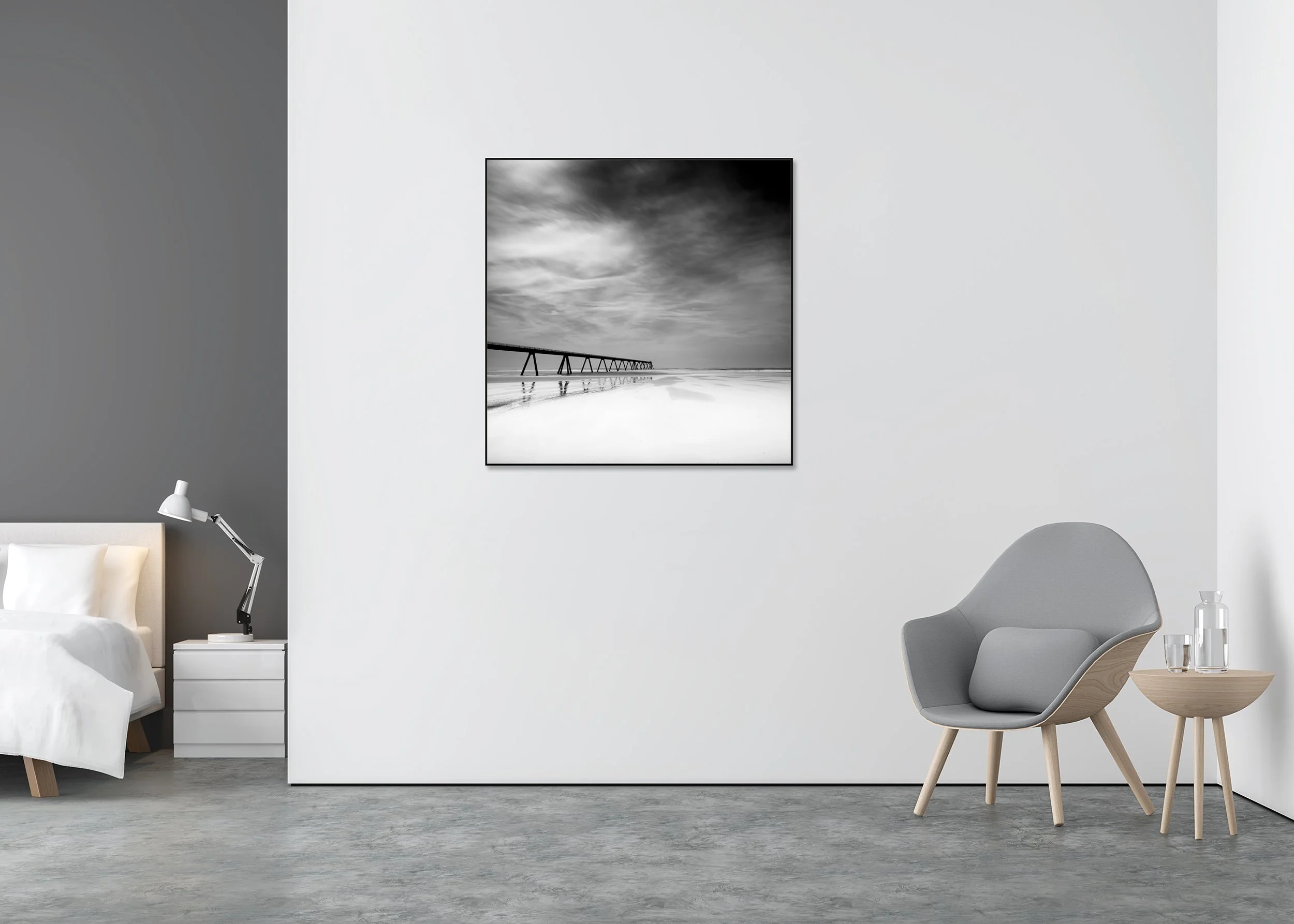 Black-and-white coastal landscape photograph with pier and reflective wet sand, shown mounted on Dibond in an aluminium ArtBox frame