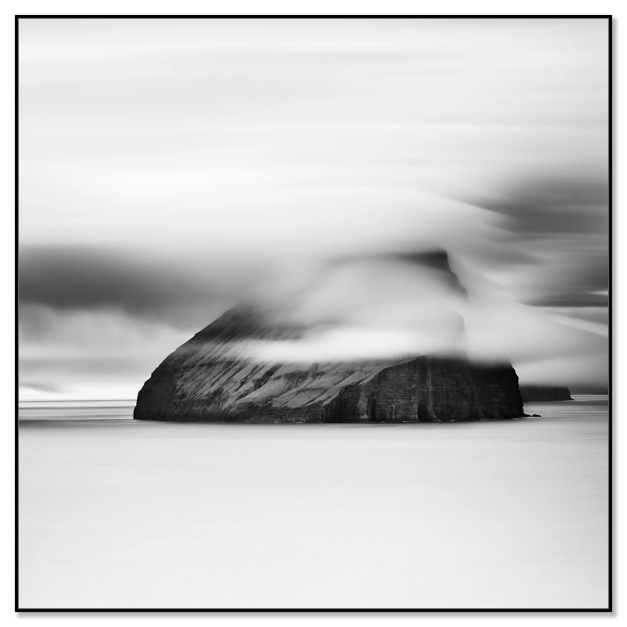 Minimalist monochrome seascape with a large sea stack, low cloud and smooth water – framed ArtBox black