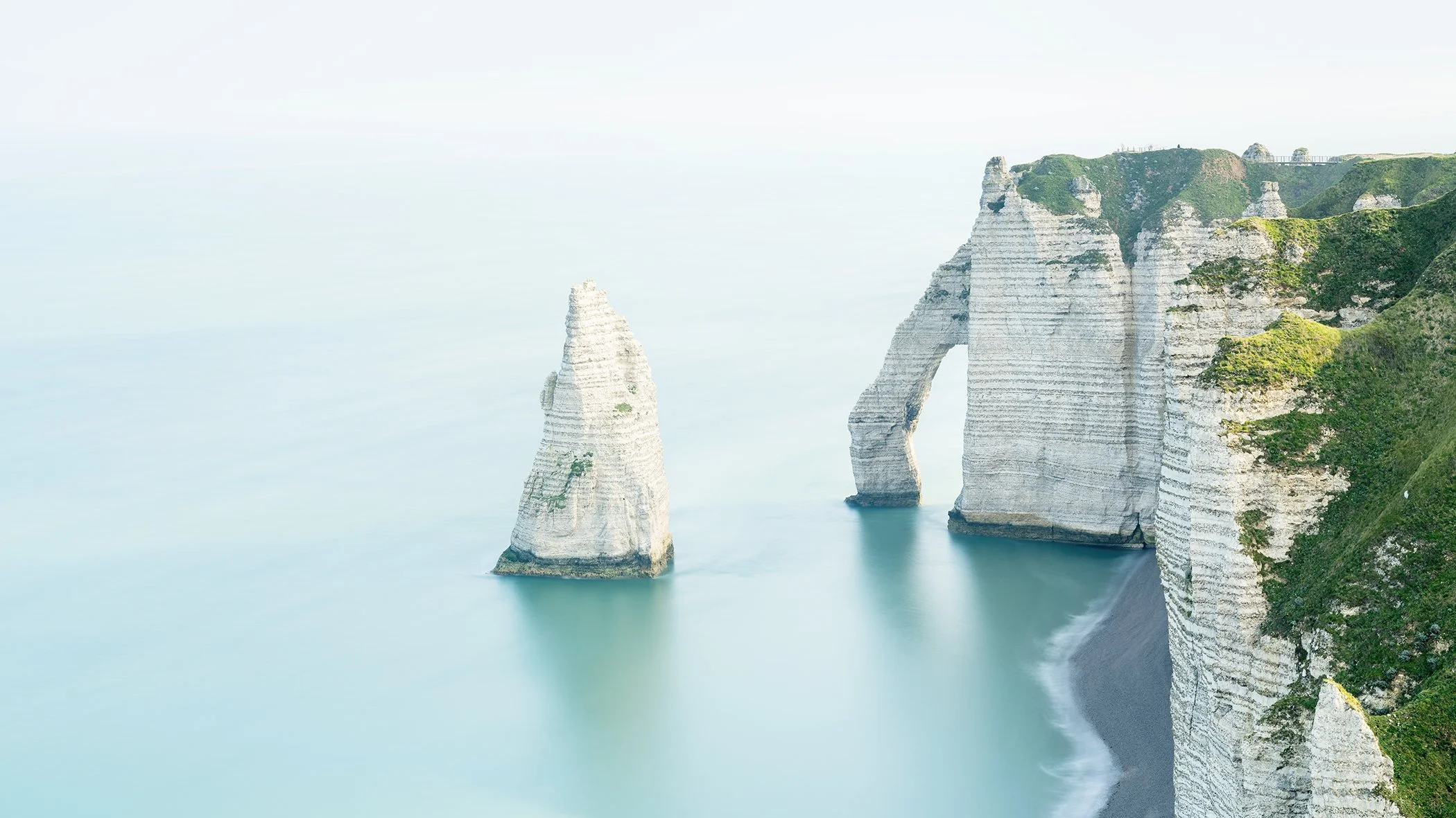 Minimalist colour long-exposure photograph of the Porte d’Aval, Aiguille and white chalk cliffs at Étretat, France. Photo by Gerald Berghammer.