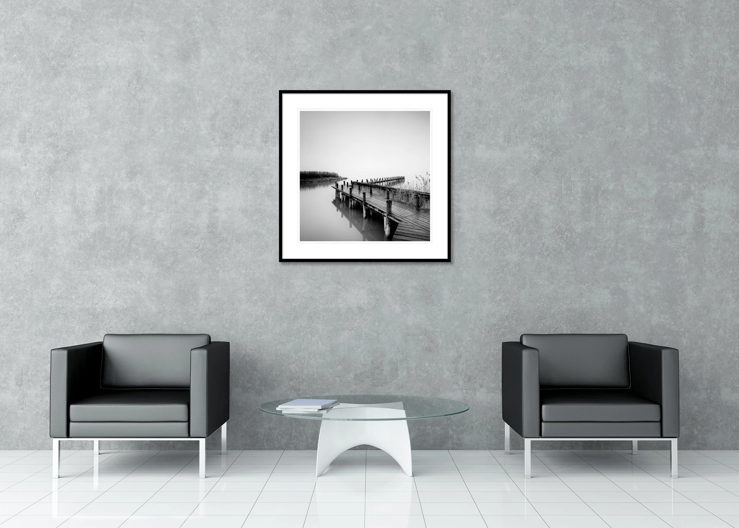 Black and white landscape print with a wooden jetty, calm reflective water and a soft misty horizon, archival pigment print in a classic frame with mount