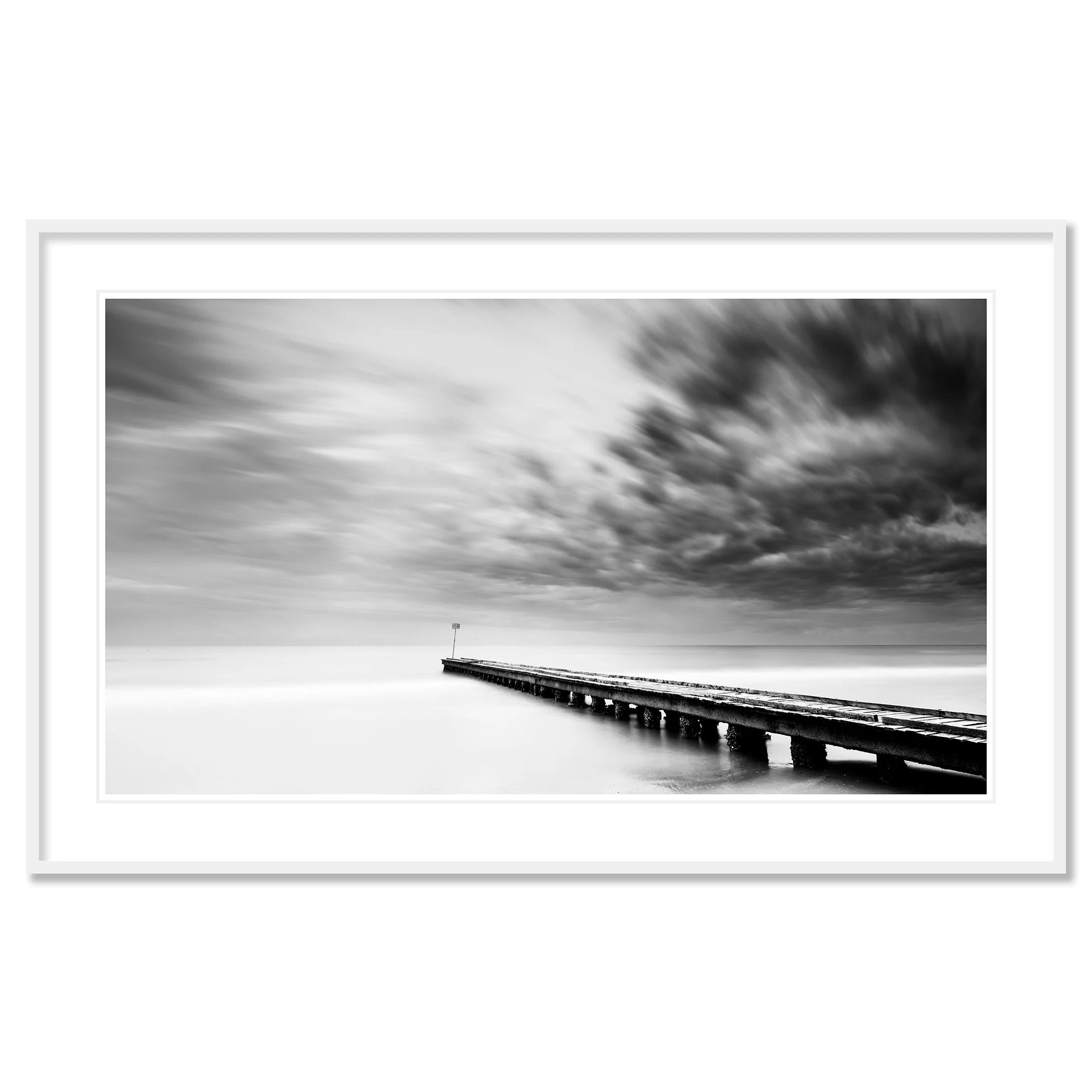 Gerald Berghammer - Black and white long exposure seascape photography. A long pier extending into a calm body of water with dramatic clouds overhead. Classic framed white