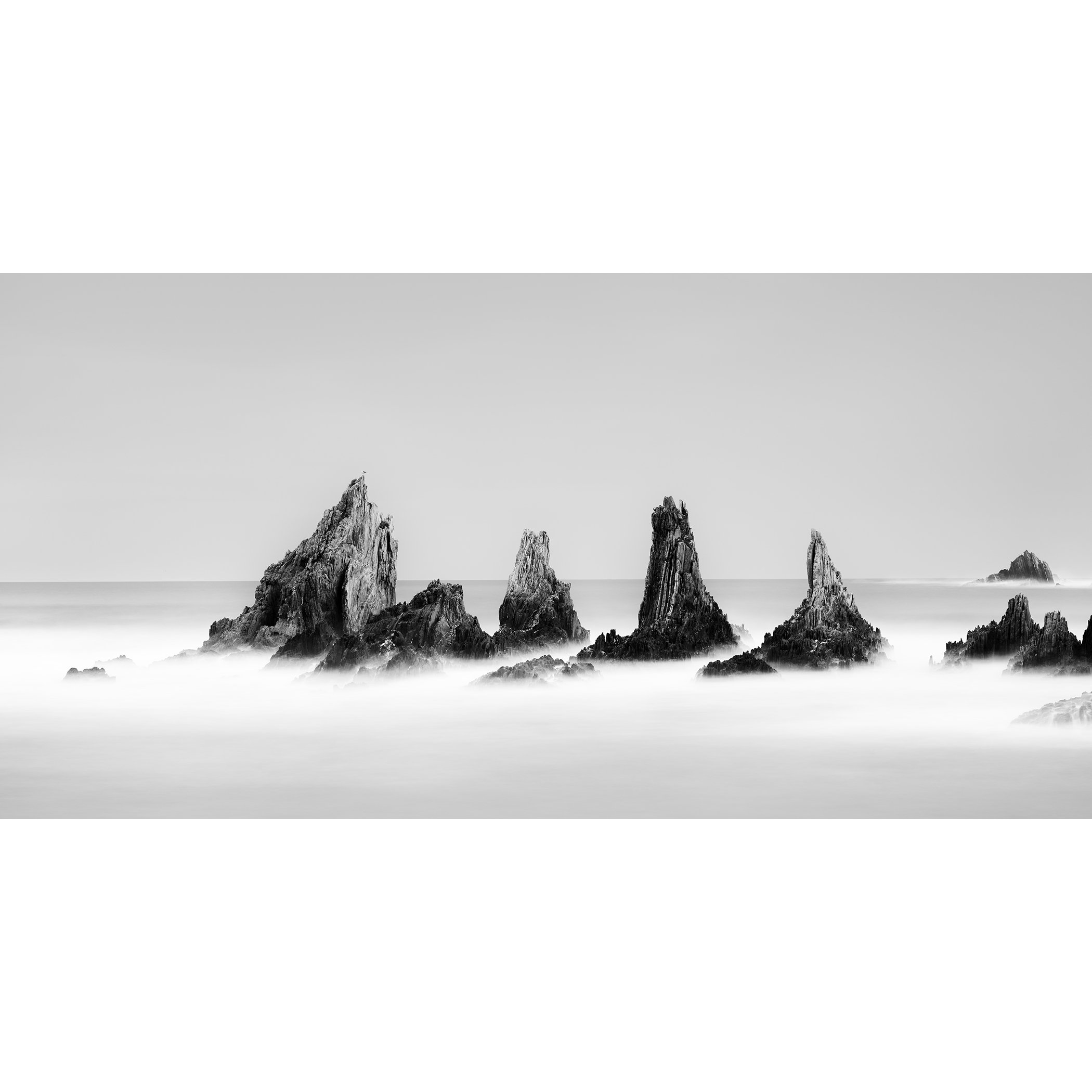 Rocky Peaks Panorama, Study 2 – minimalist black-and-white long-exposure seascape of jagged rock formations in Spain by Gerald Berghammer.