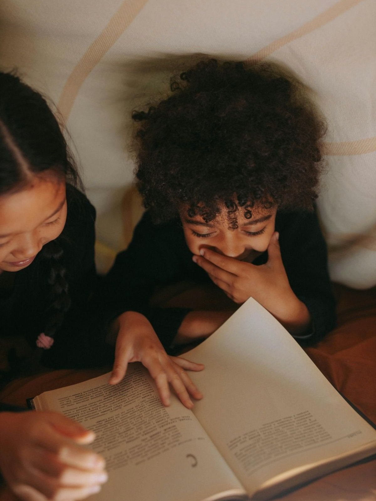 Two girls reading a book laying down