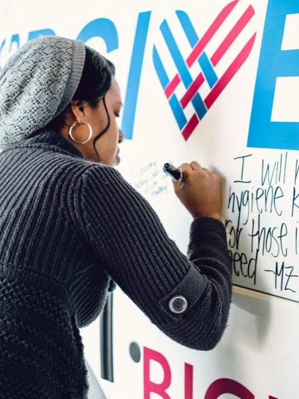 A woman signs a Giving Tuesday sign.