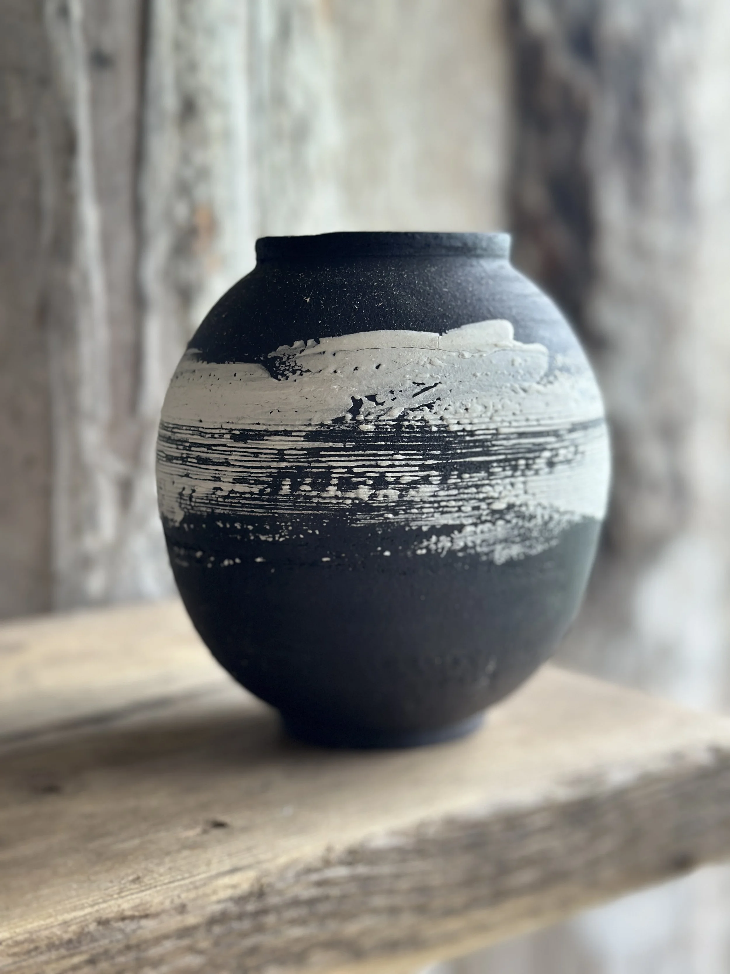 A black stoneware clay round pot with a white slip decoration part of the monochrome range