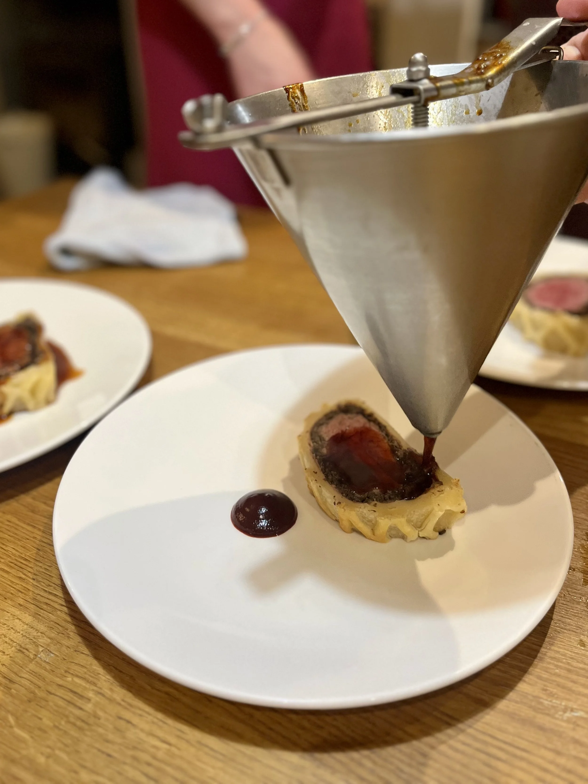 Chef piping sauce onto a ravioli with a squeeze bottle in a restaurant