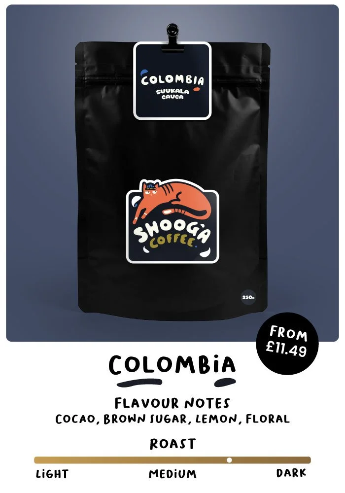 Black coffee bag labeled 'Colombia Suukala Cauca' with Shooga Coffee logo featuring an orange cat. Flavour notes: cocoa, brown sugar, lemon, floral. Roast level: medium. Price from £11.49. Available in 250g and 500g bags.