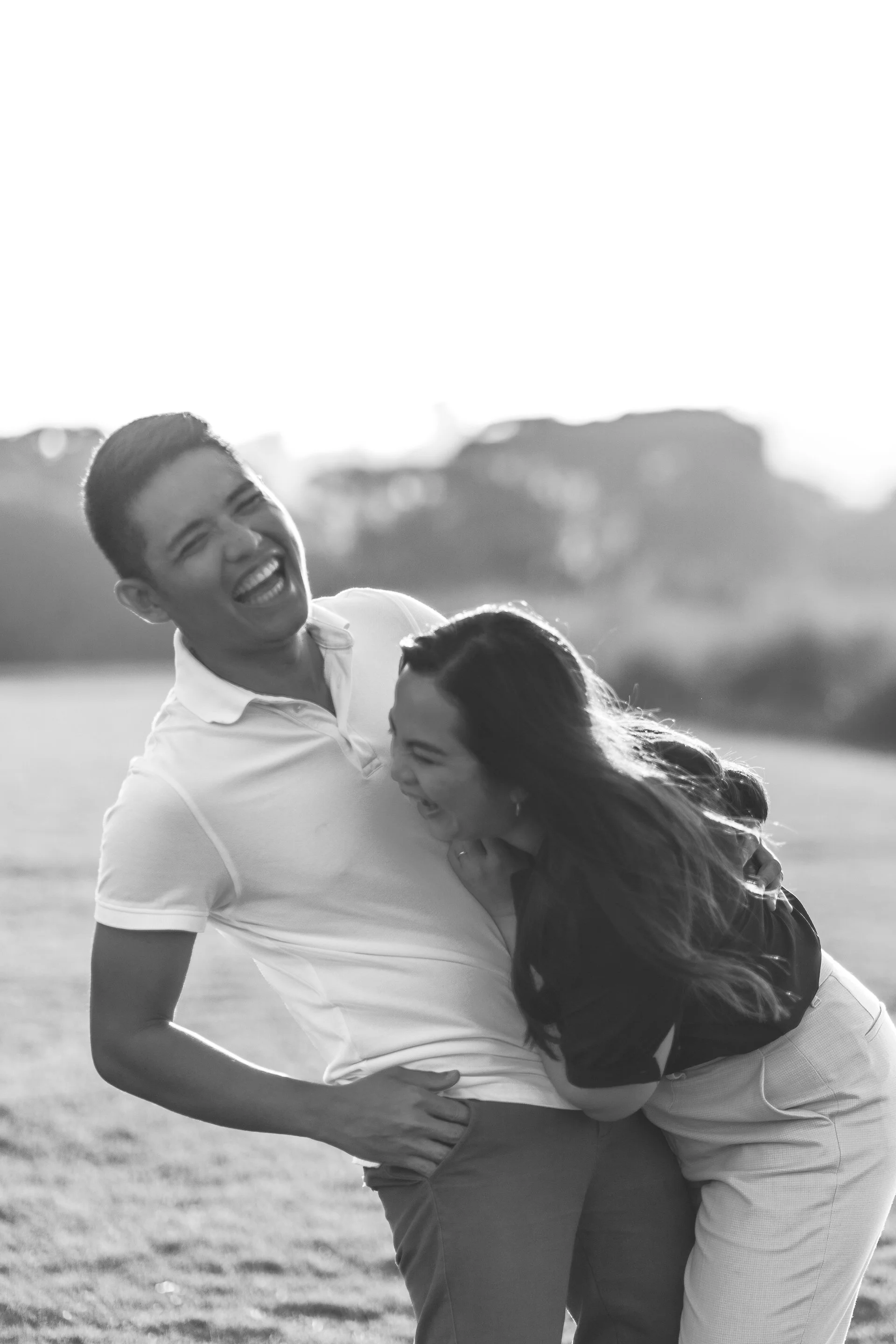 Black and white photo of a laughing man and woman outdoors in a lush green park in Torquay, Geelong, Australia
