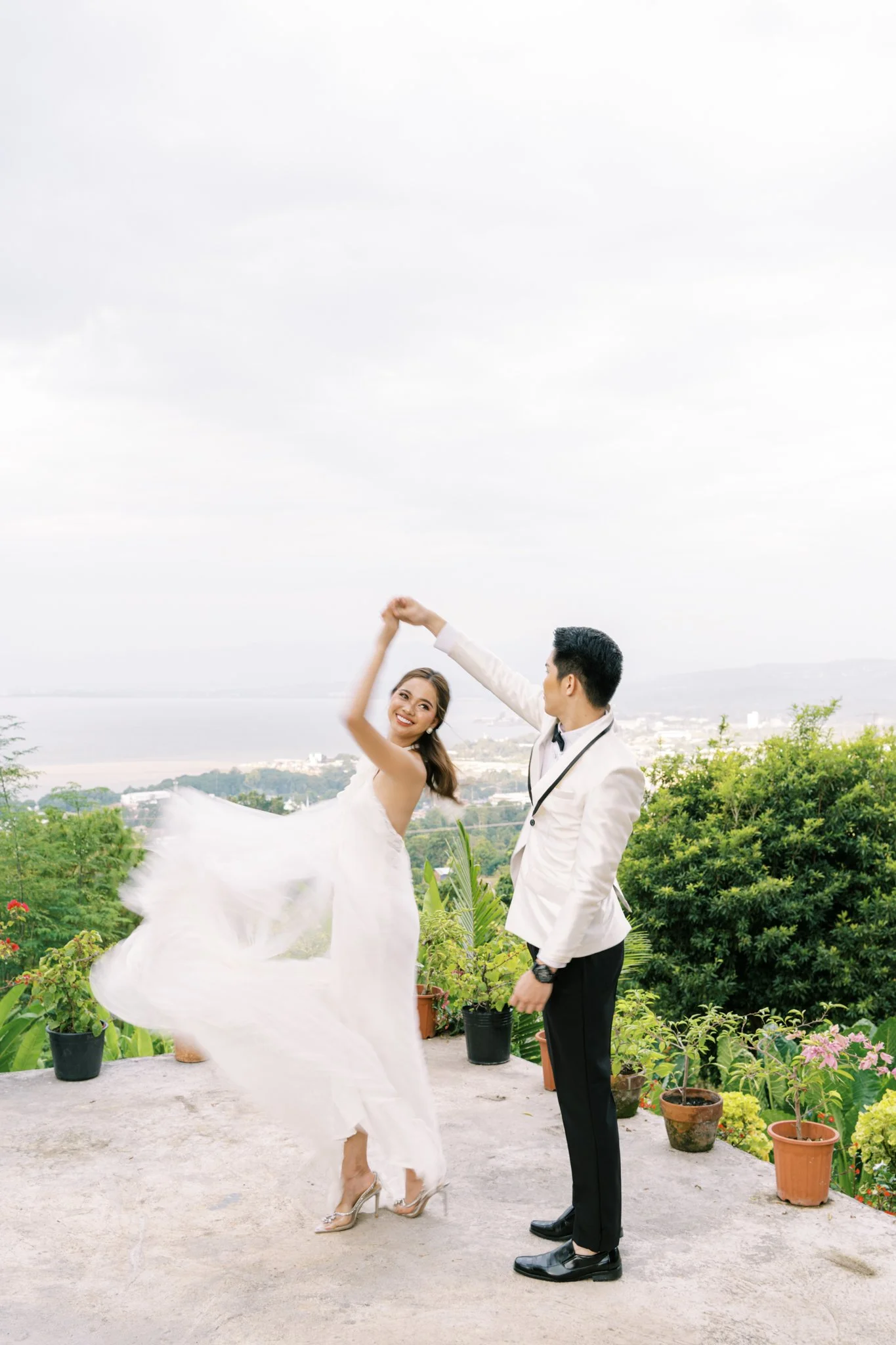 A couple dressed formally dancing outdoors with a scenic view in the background.