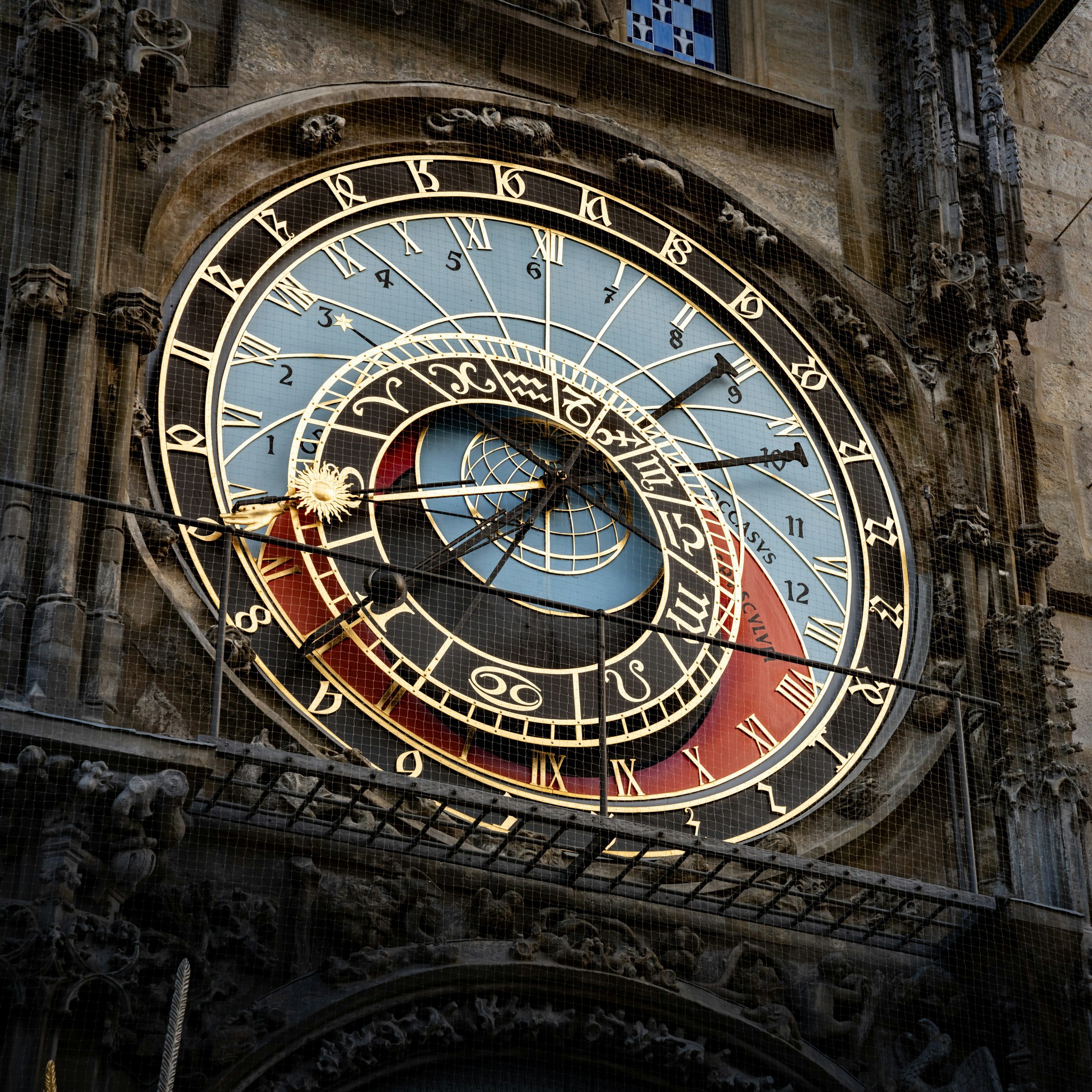 Horloge astronomique ornée de chiffres romains, avec plusieurs cadrans et détails décoratifs complexe, situé sur une façade en pierre d'un bâtiment historique.