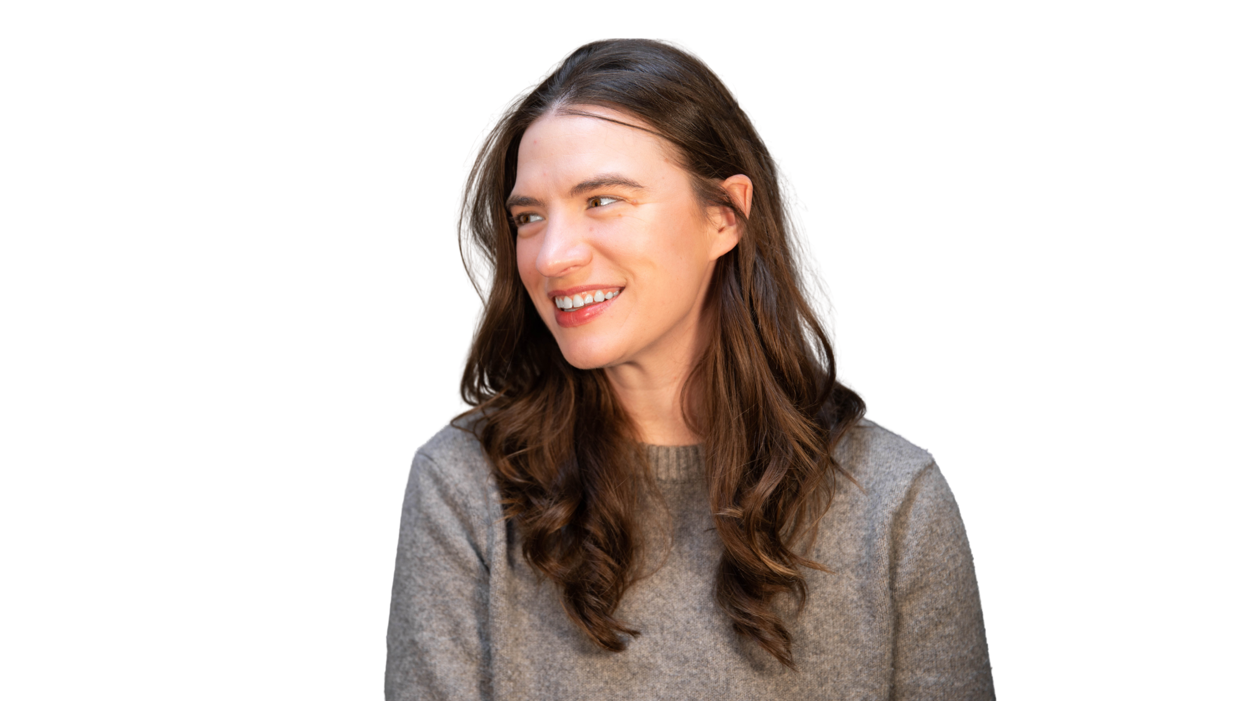 A woman with long brown hair and fair skin smiling and looking to her left, wearing a gray sweater.