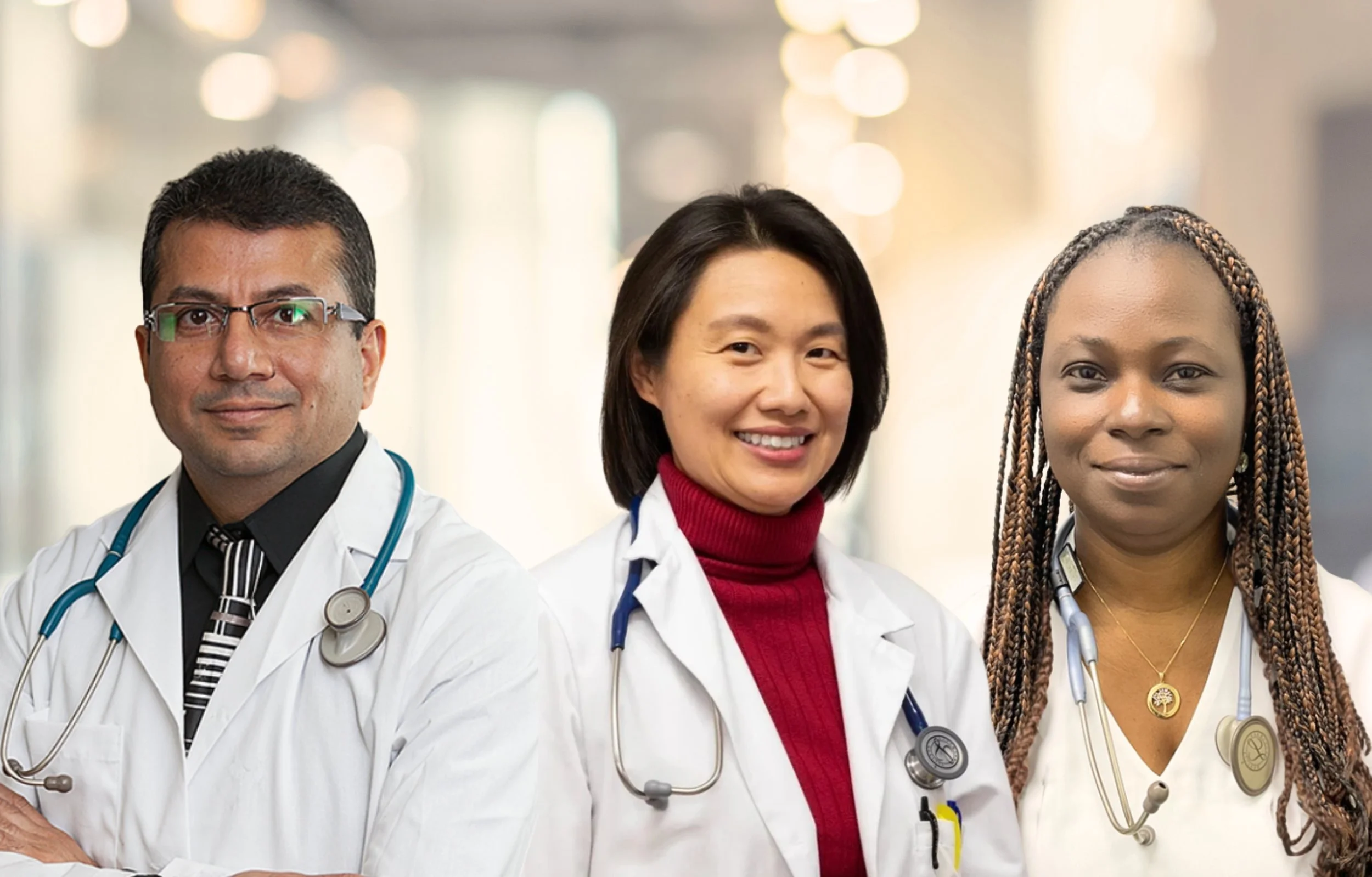 Three diverse medical professionals in white coats with stethoscopes, standing confidently in a hospital or clinic setting.