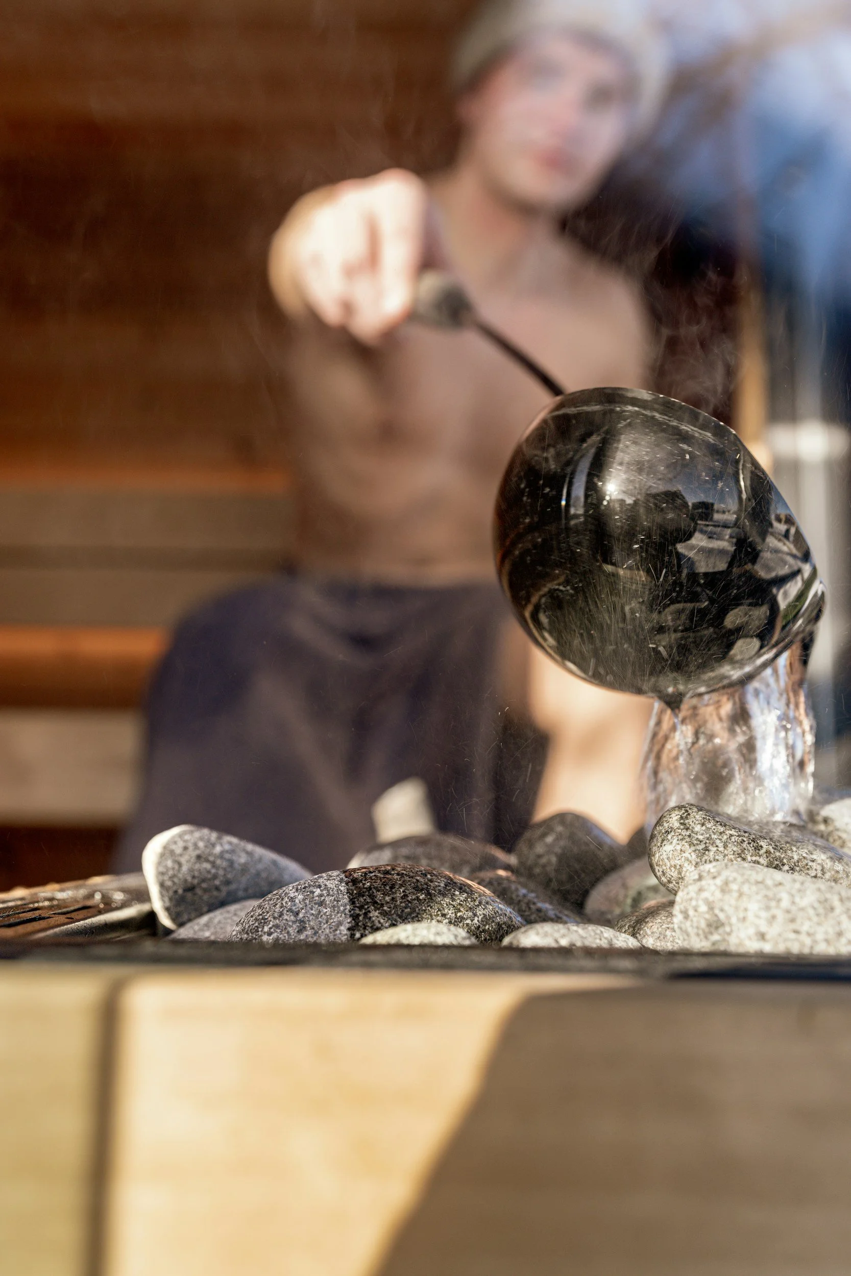 Water being poured over hot sauna stones during a Whitby Wellbeing wild sauna session