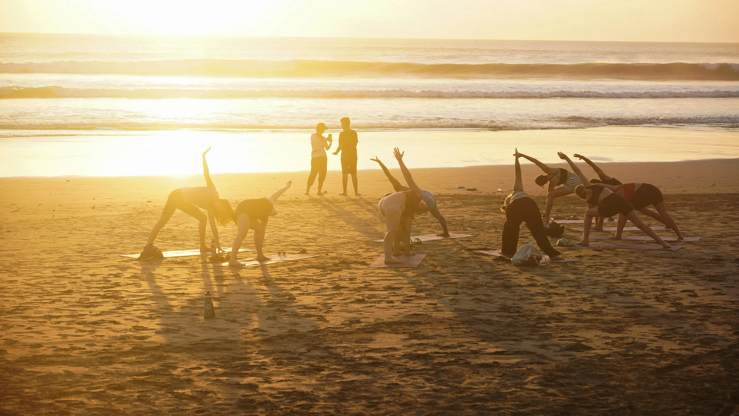 Outdoor yoga class on the beach at sunrise on the Yorkshire Coast.