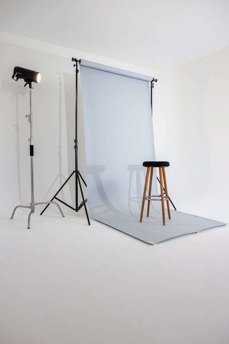 Fotostudio mit Beleuchtung, Hintergrund und Sitzhocker auf weißem Boden