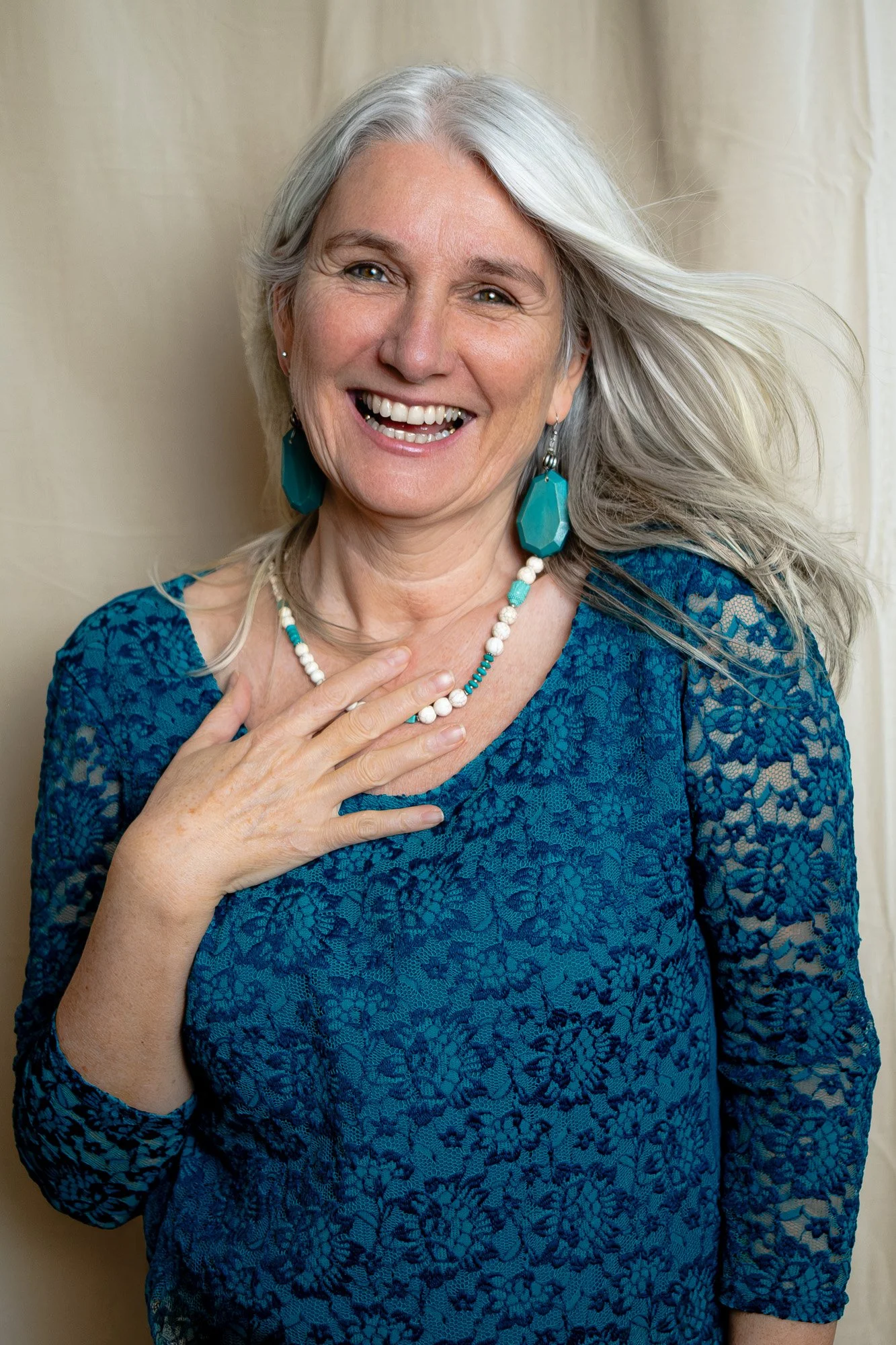 Lachende Frau mit silbernen Haaren vor hellem Vorhang, Portrait-Shooting im studio cliq Mainz