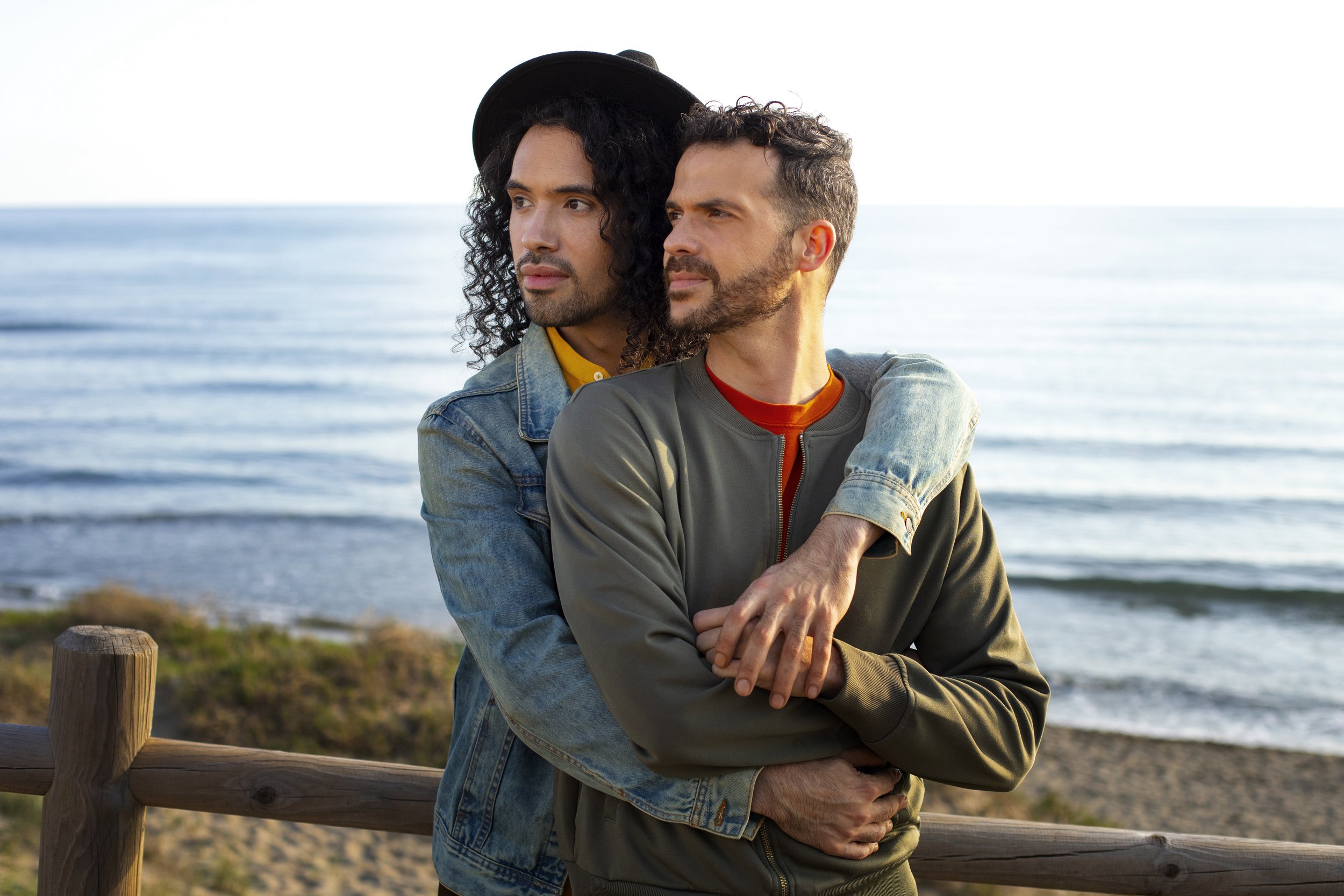 Couple LGBTQ+ partageant un moment complice au bord de la mer, symbolisant l’amour et l’acceptation.