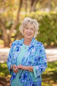 Smiling woman standing outdoors wearing a blue patterned jacket