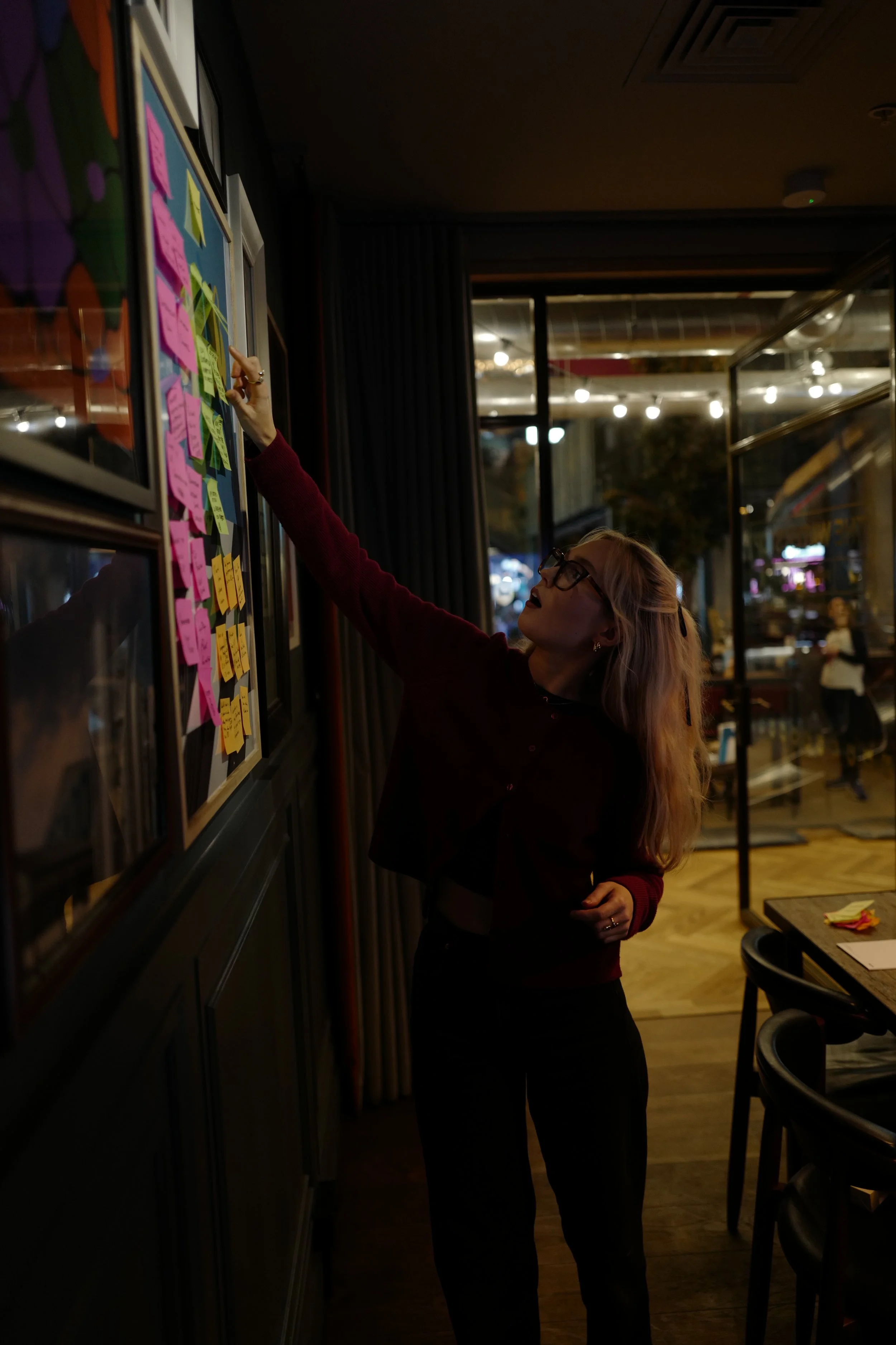 Person reaching for sticky notes on a wall in dimly lit room