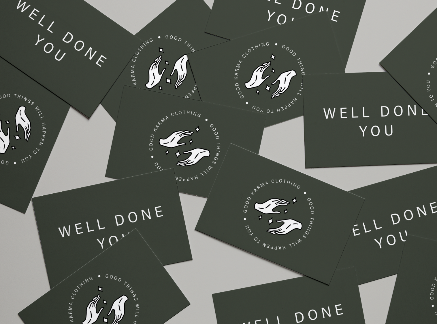 Scattered business cards with 'Well Done You' and 'Good Karma Clothing' logo featuring two hands.