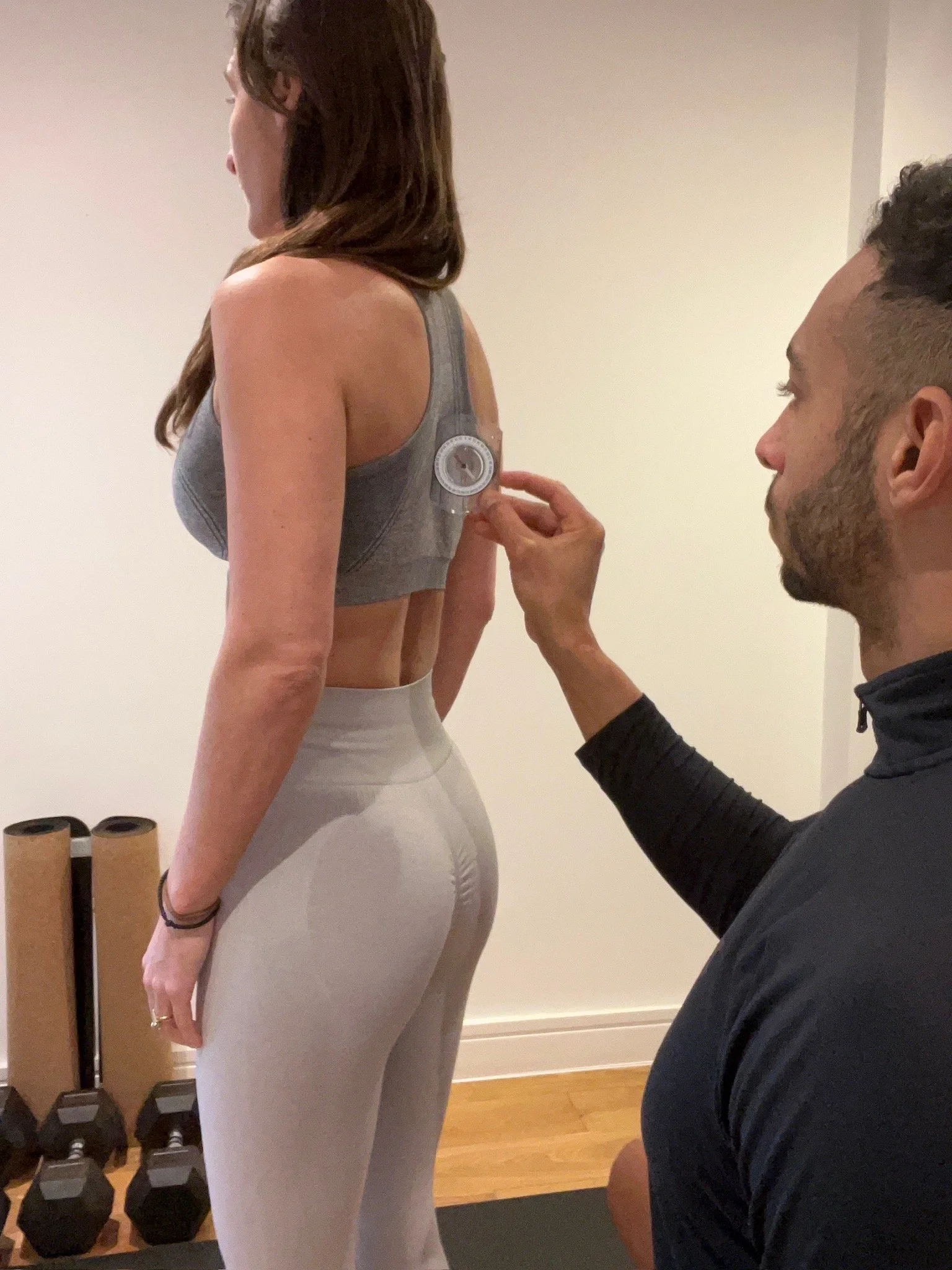 Personal trainer conducting a live posture assessment on a female client using specialised posture testing equipment.