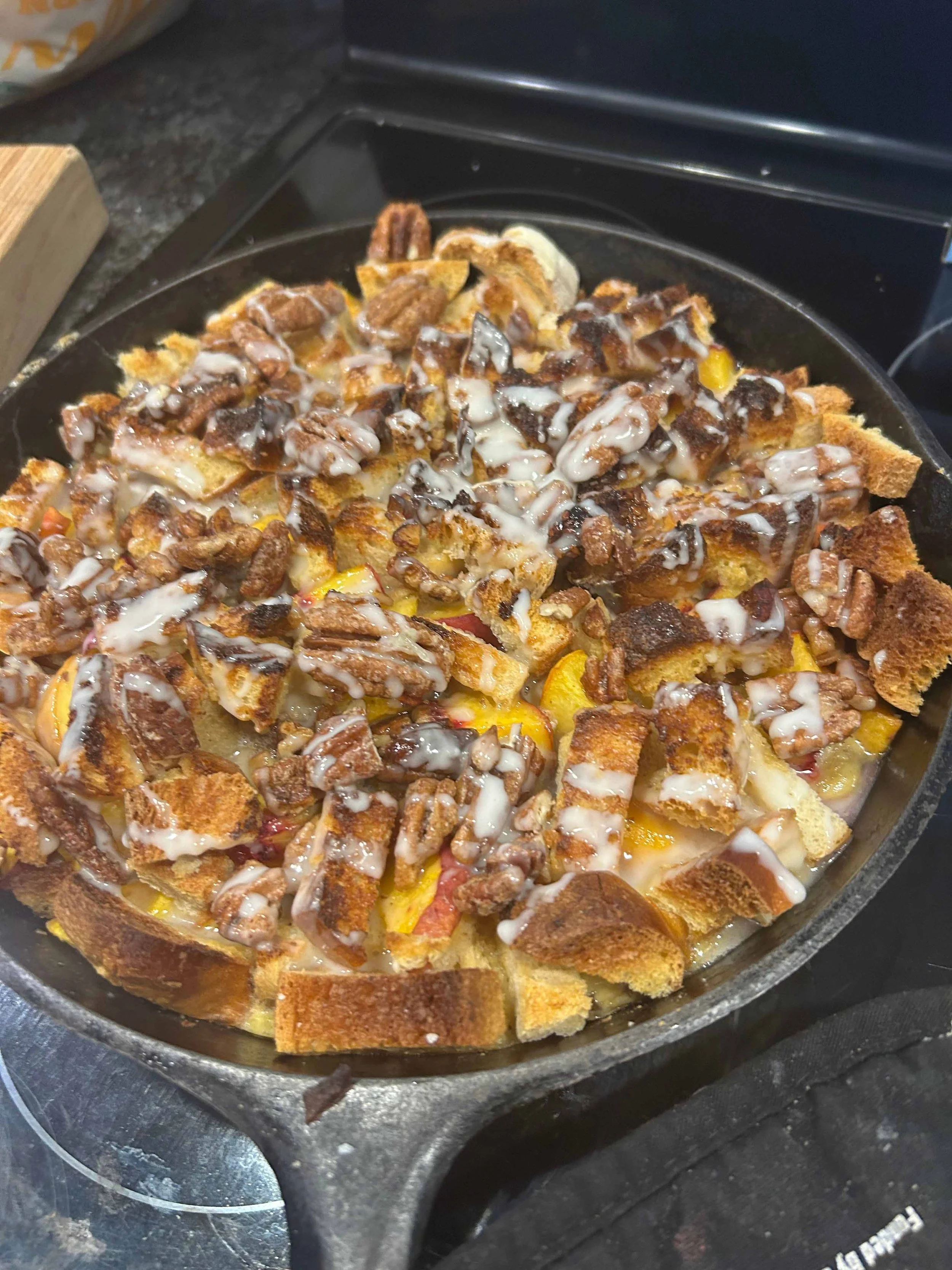 Golden baked pecan bread pudding in a cast iron skillet topped with Prime Pecan Halves