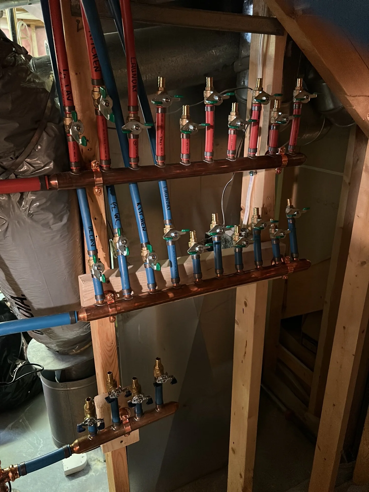 Working on new hot and cold water manifolds with labelled lines and individual shut-off valves installed by Studio Plumbing