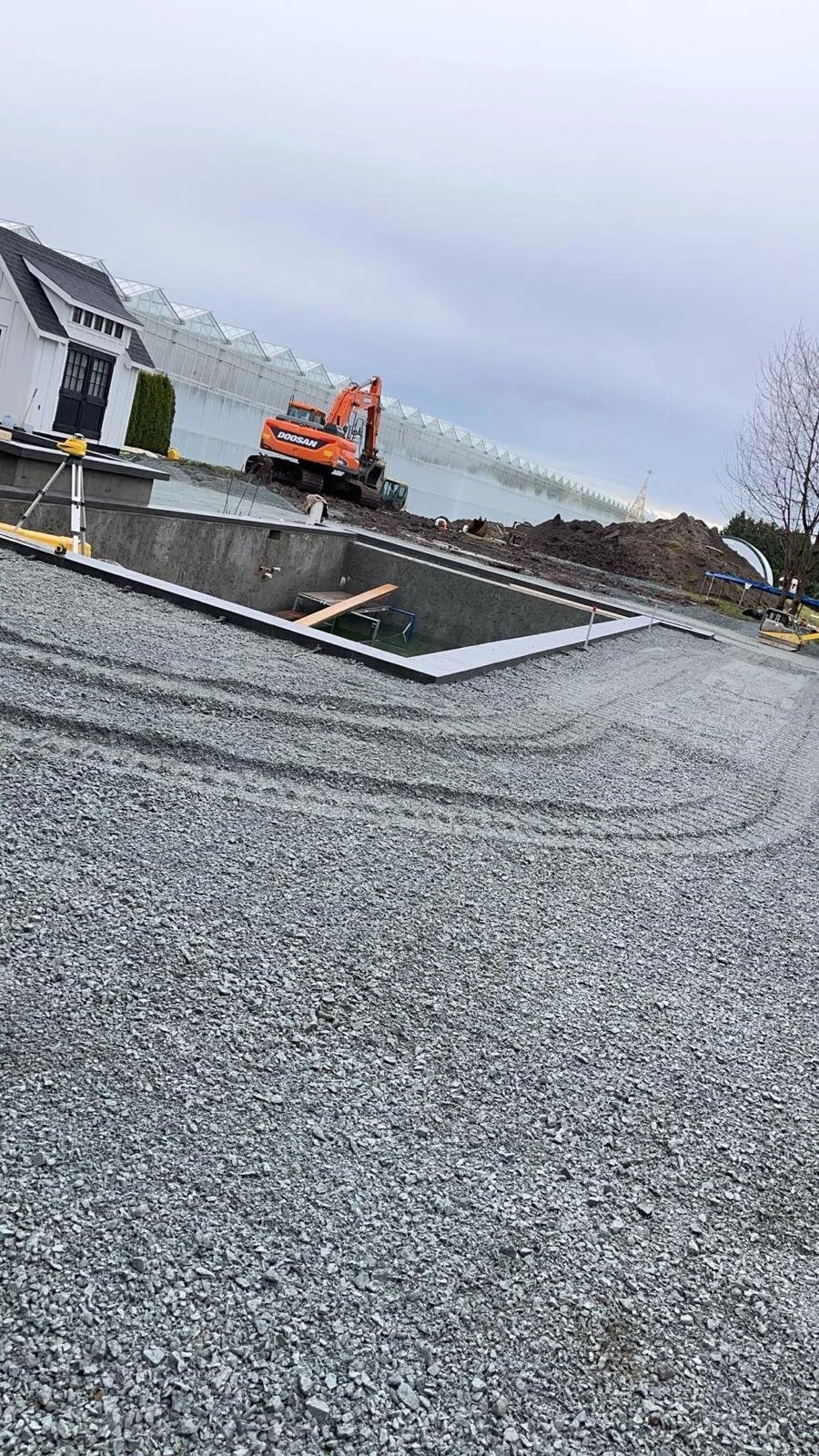 Construction site with excavator, gravel, and concrete structure