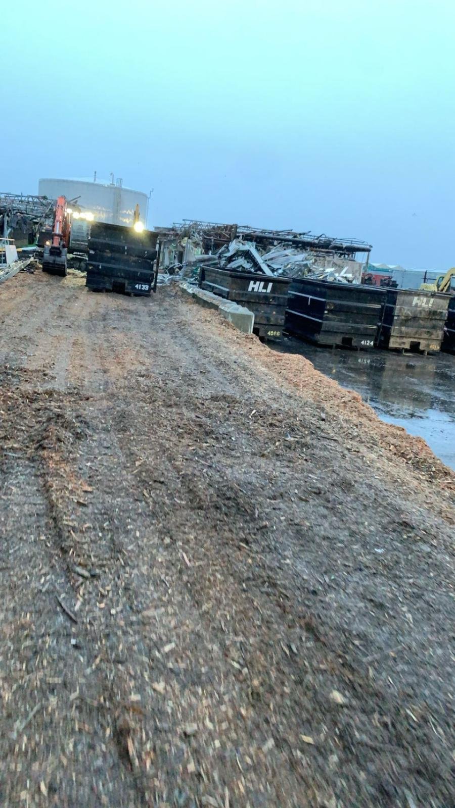 Construction site with dirt road, heavy machinery, and containers.