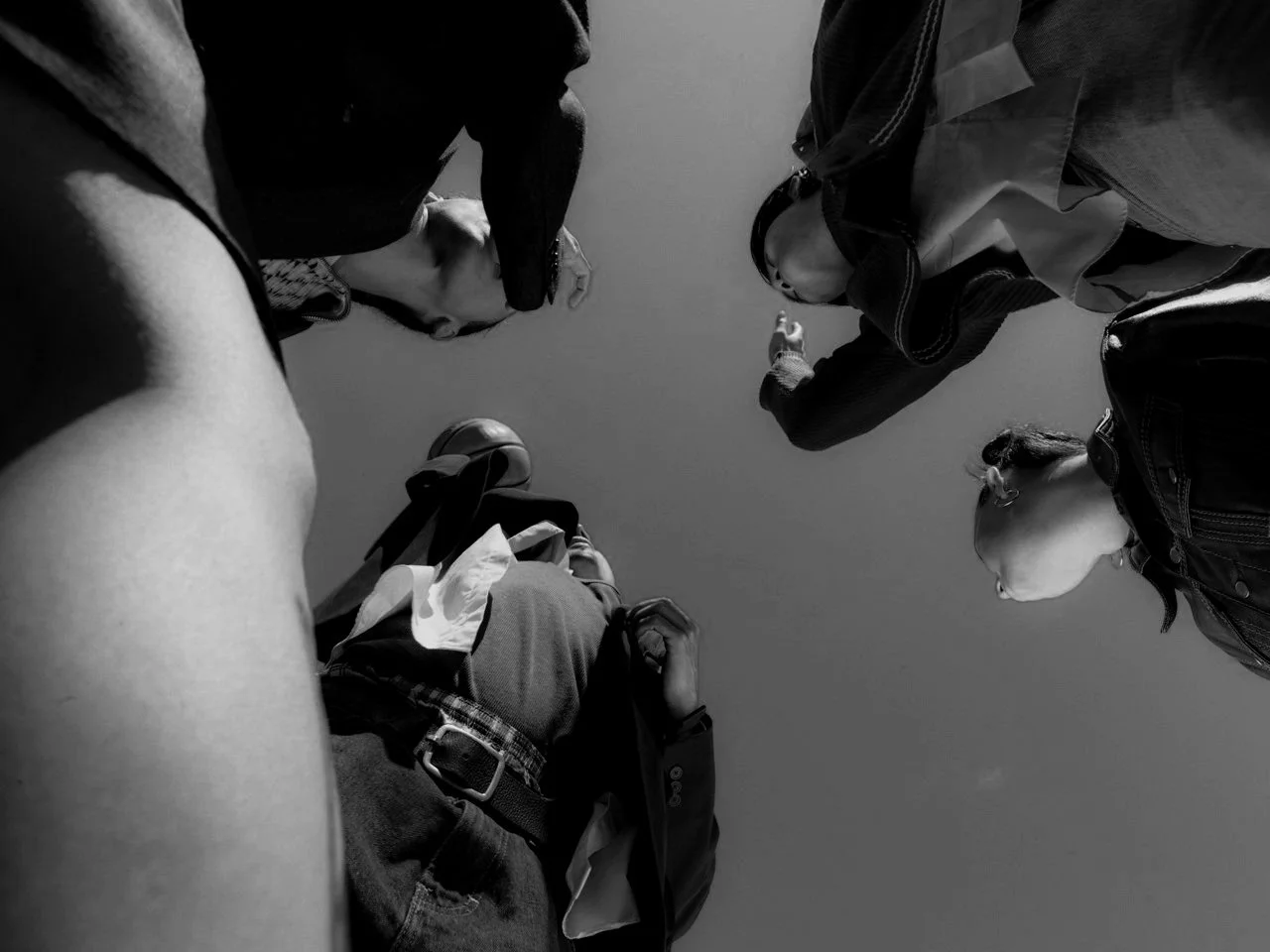 People standing in a circle, viewed from below, on a clear sky background.