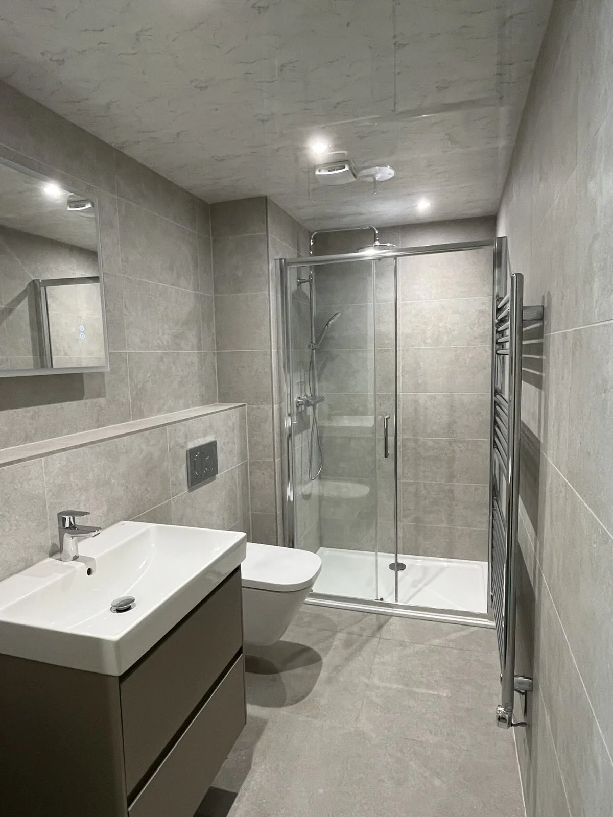 Modern fully tiled bathroom, wall hung vanity unti & sink, wall-mounted toilet, glass-enclosed shower stall, LED mirror with bluetooth & shaver
socket , and heated towel rail.