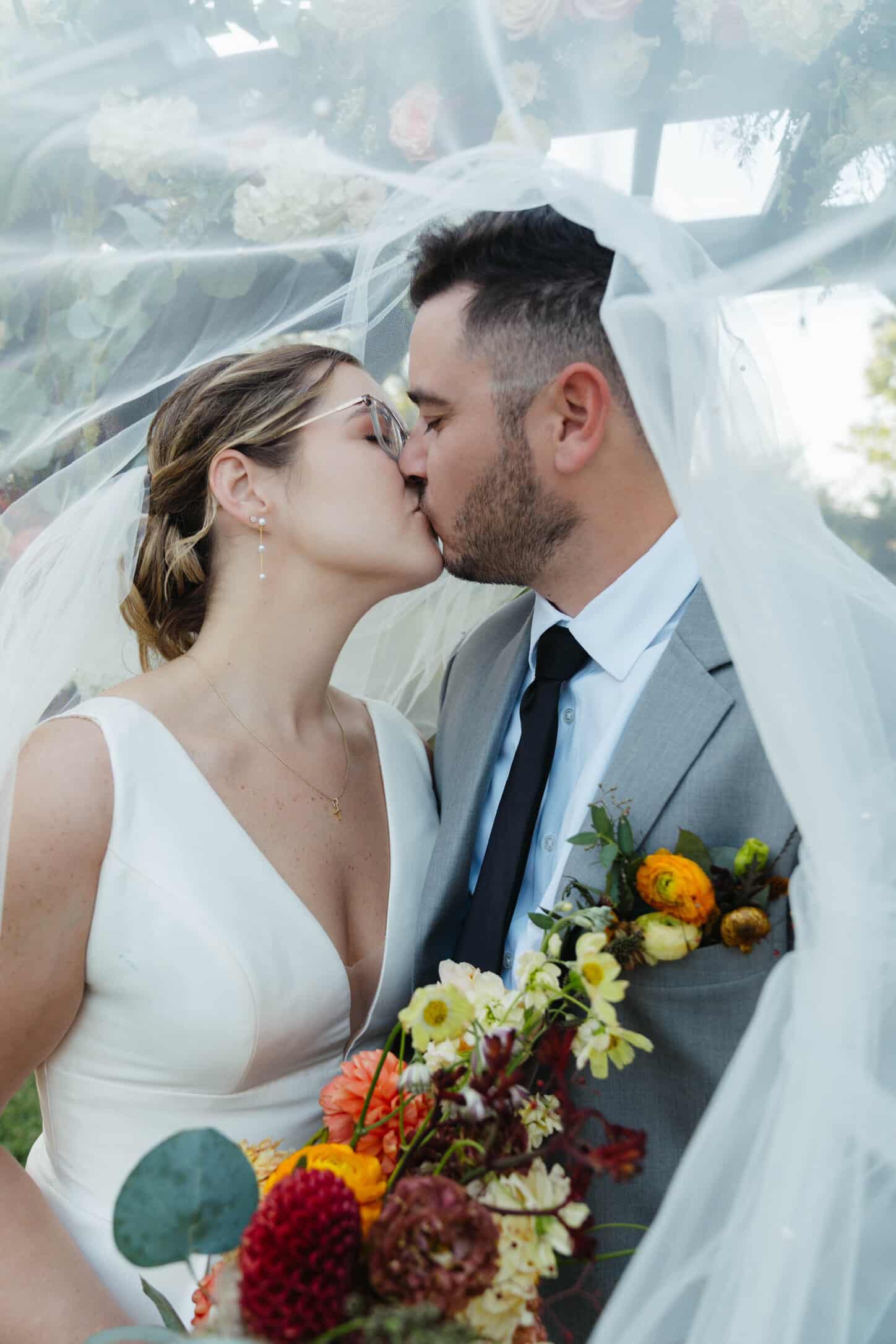 Bride and Groom under veil kissing