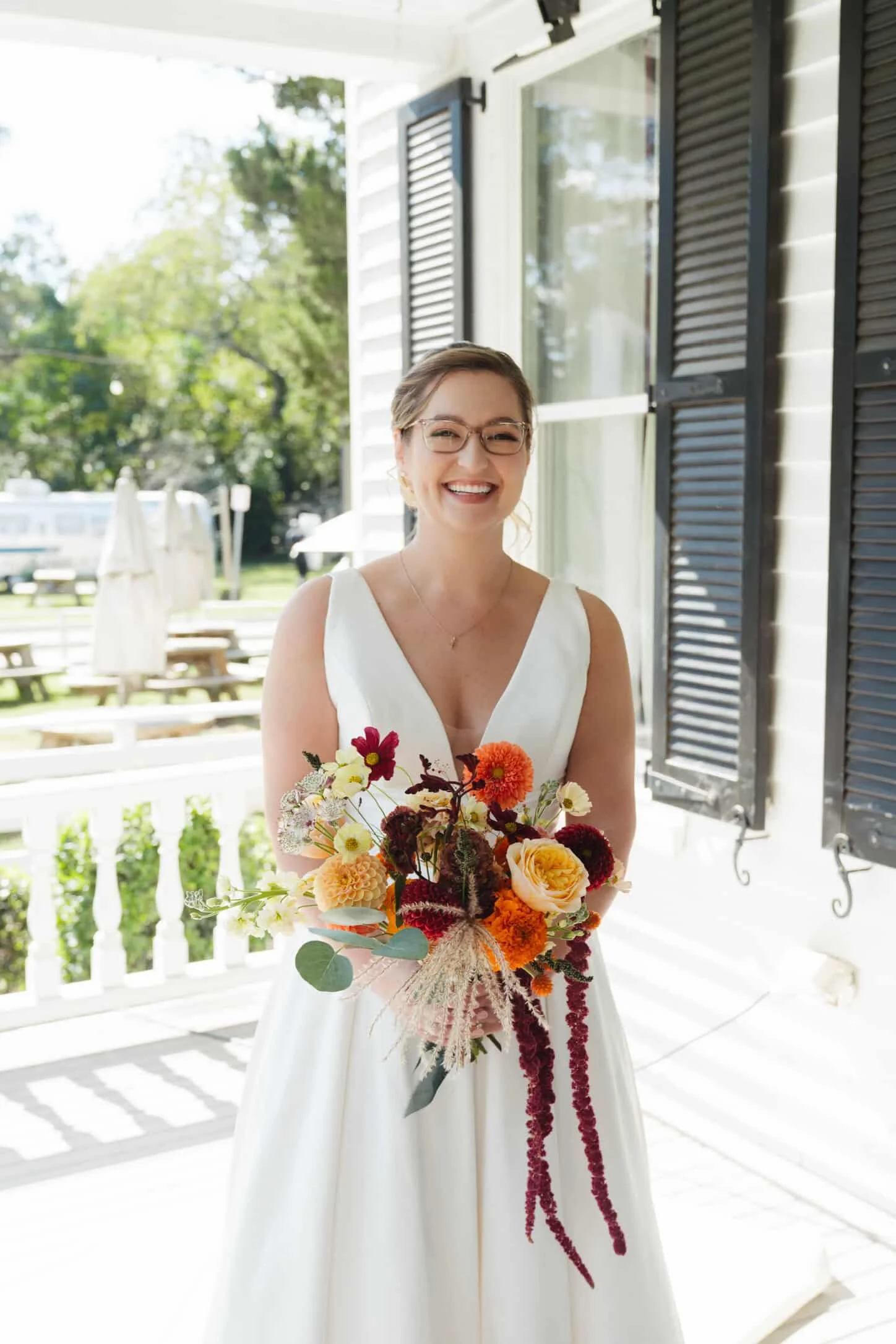 Bride on porch holding fall colored flowers