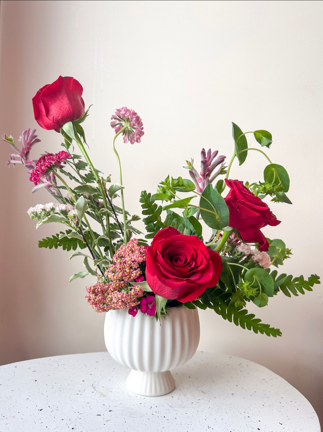 Red Roses in white footed compote with pink filler flowers